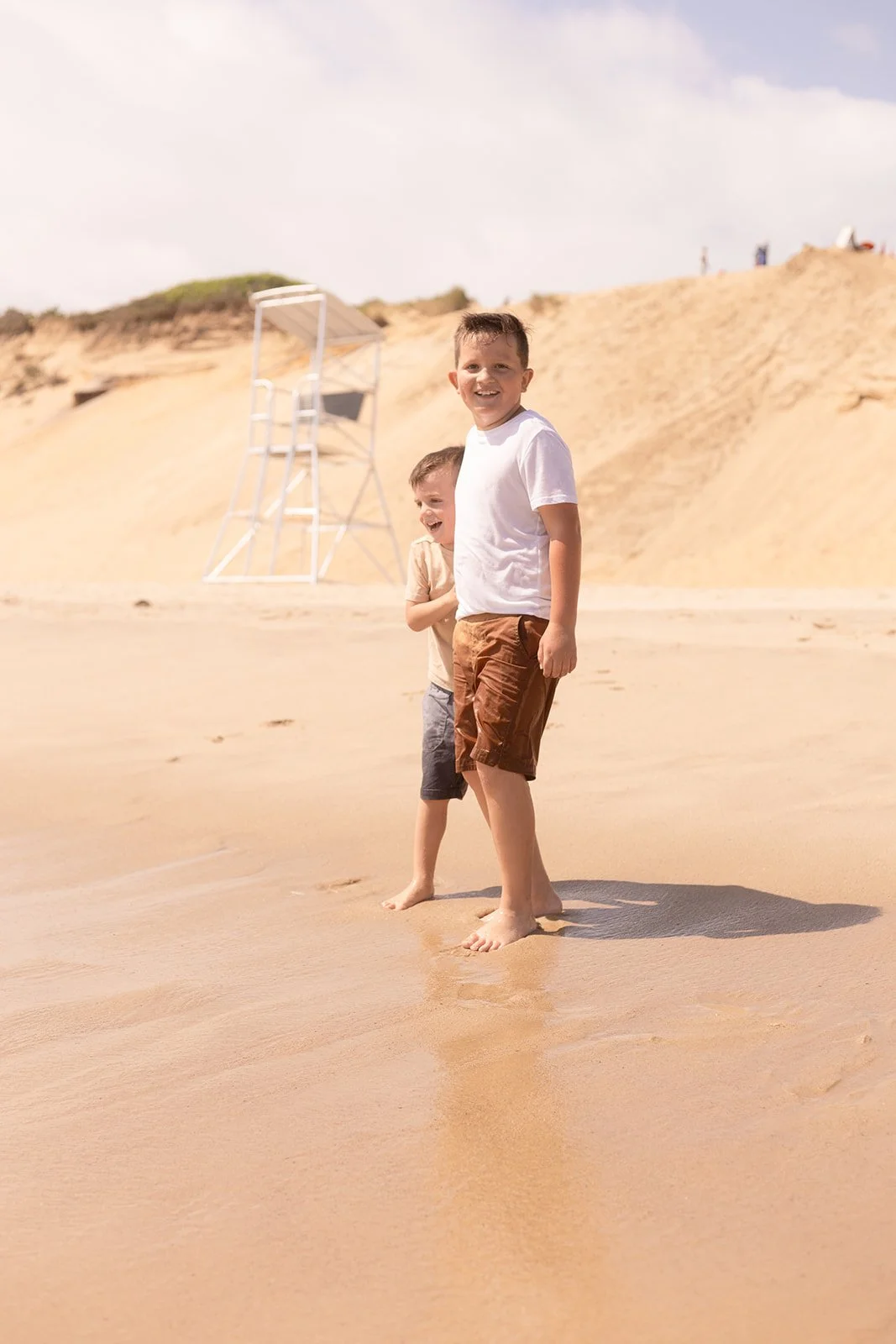 Two boys playing in the ocean during a Cape Cod family photography session, capturing movement and personality