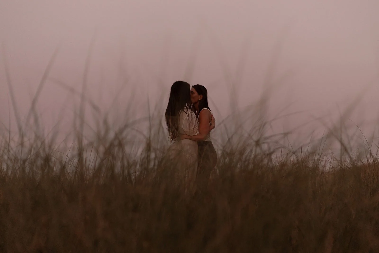 LGBTQ+ couple walking hand in hand through a marsh on Cape Cod during a golden hour anniversary photography session