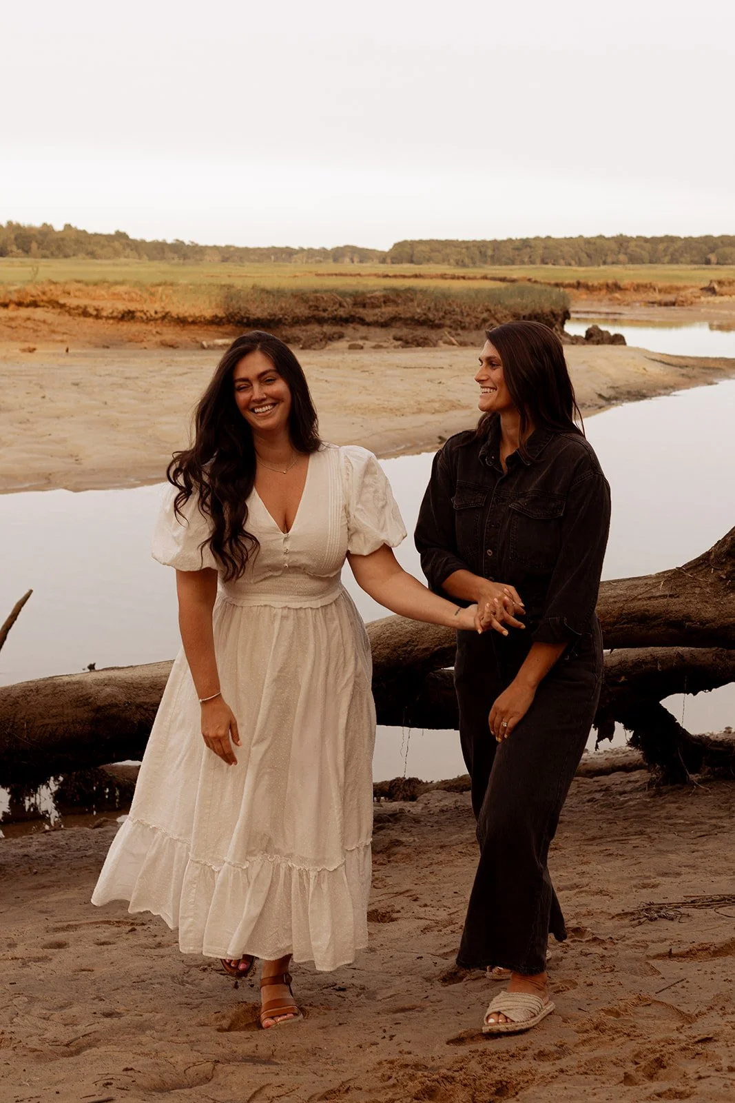 LGBTQ+ couple walking hand in hand through a marsh on Cape Cod during a golden hour anniversary photography session