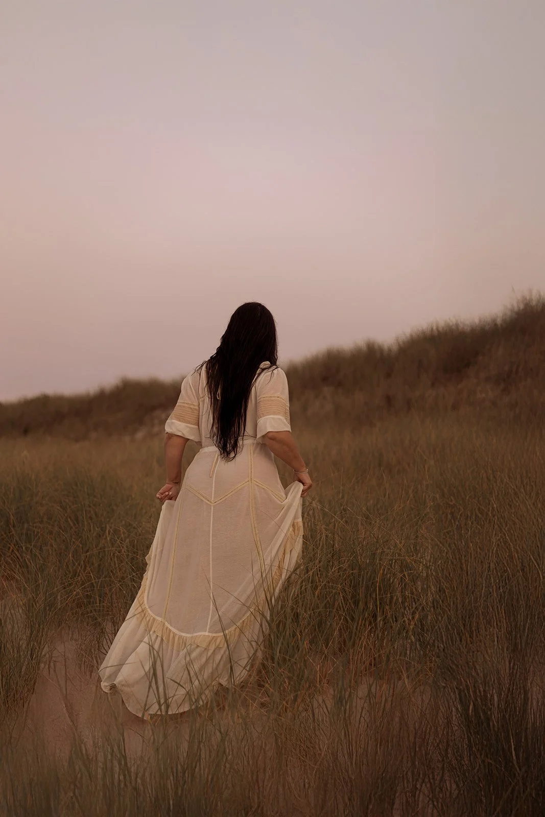 LGBTQ+ couple walking through an open field at sunset, warm cinematic tones in a relaxed outdoor photography session