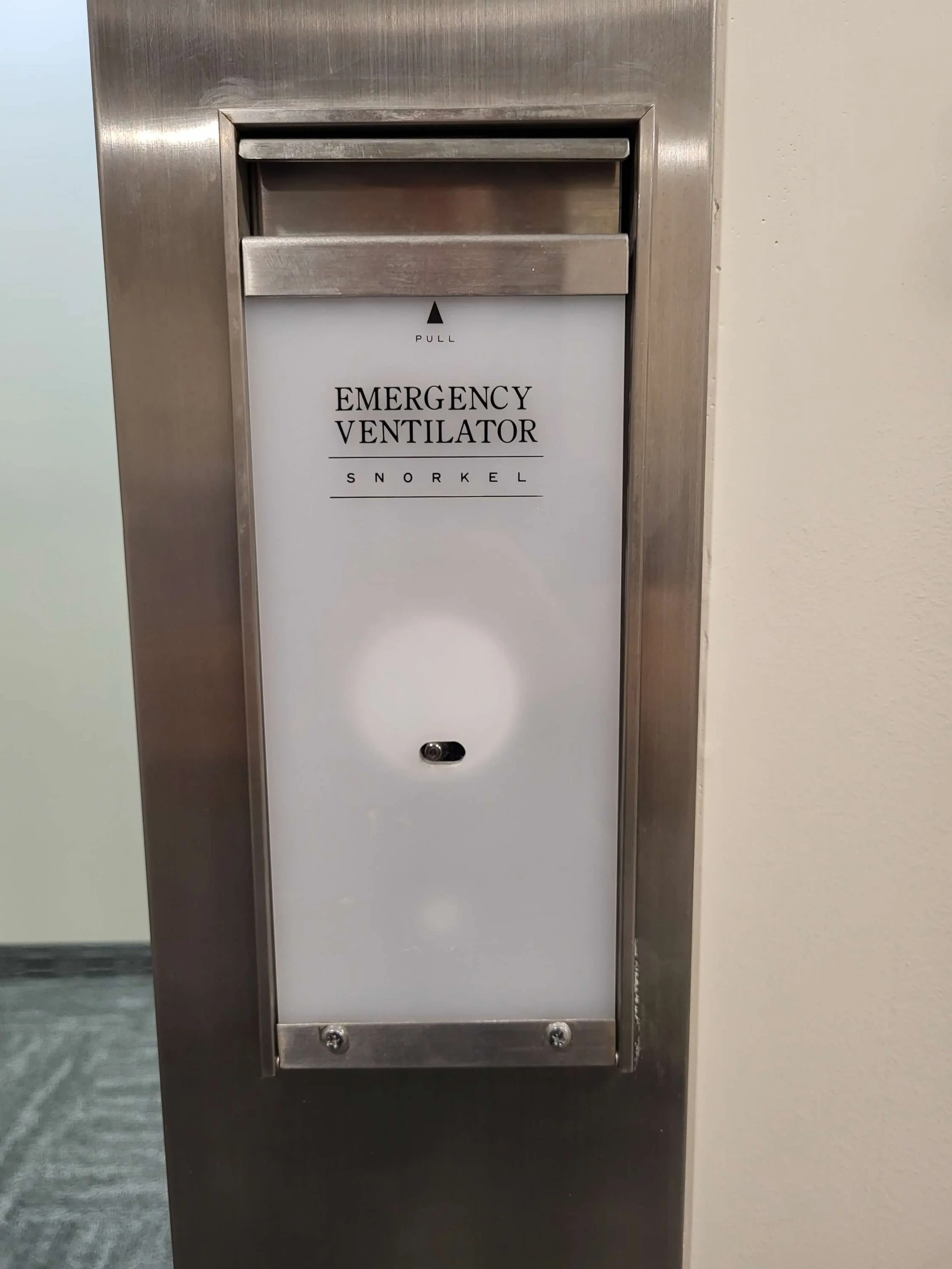 A stainless steel emergency ventilator cabinet with a white panel labeled 'Emergency Ventilator Snorkel' and an arrow pointing up labeled 'Pull' at the top.