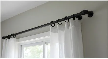 Curtain rod with rings holding white curtains above a window