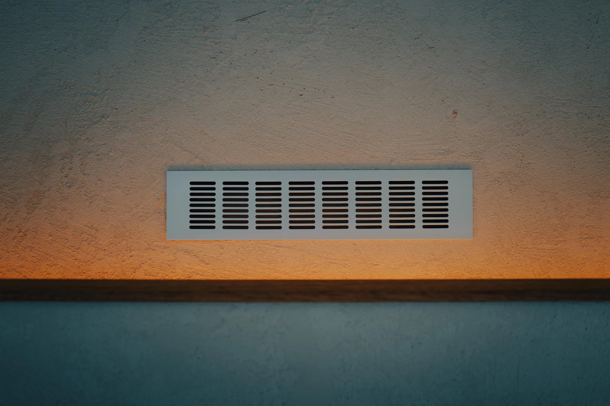 NUUT Aewol 눗애월 Wall vent with horizontal slats on a beige wall, illuminated by warm light.