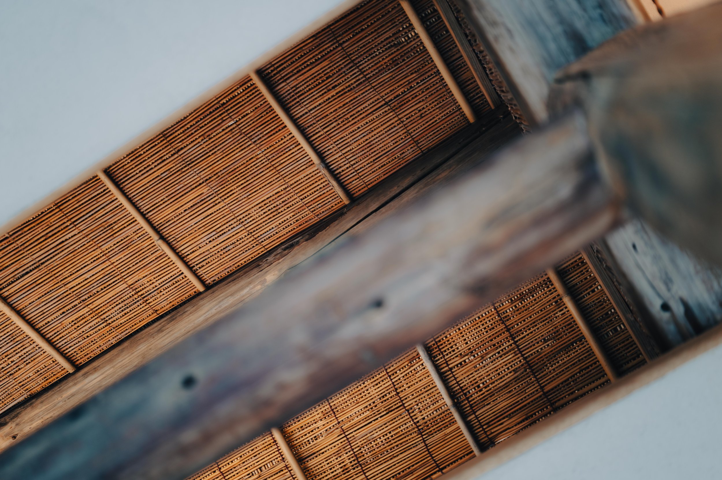 NUUT Aewol 눗애월 Close-up of a wooden object with a woven bamboo or reed surface on top, possibly a traditional mat or mat-lined container.