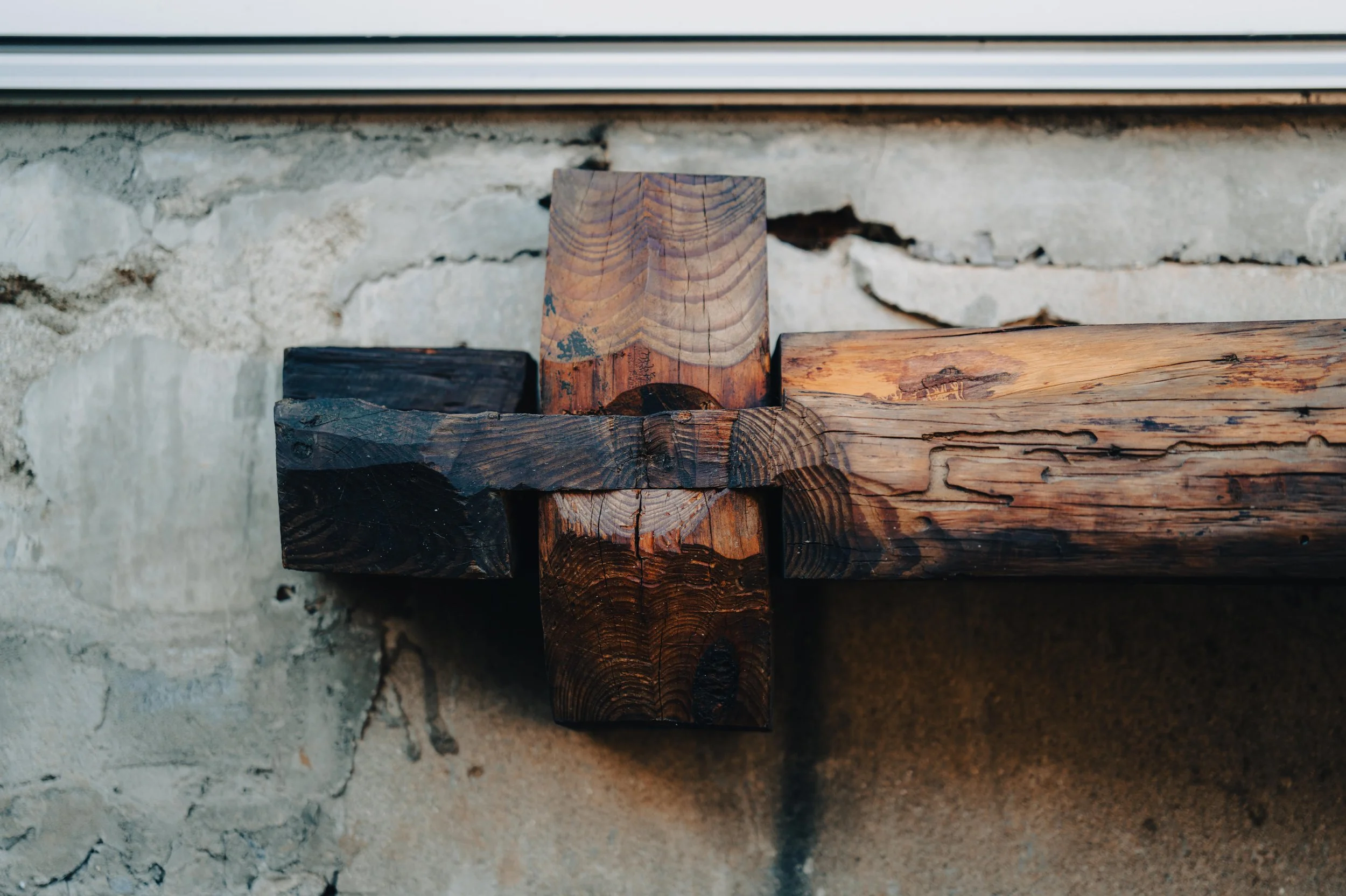Close-up of a wooden bench with a stone wall background.