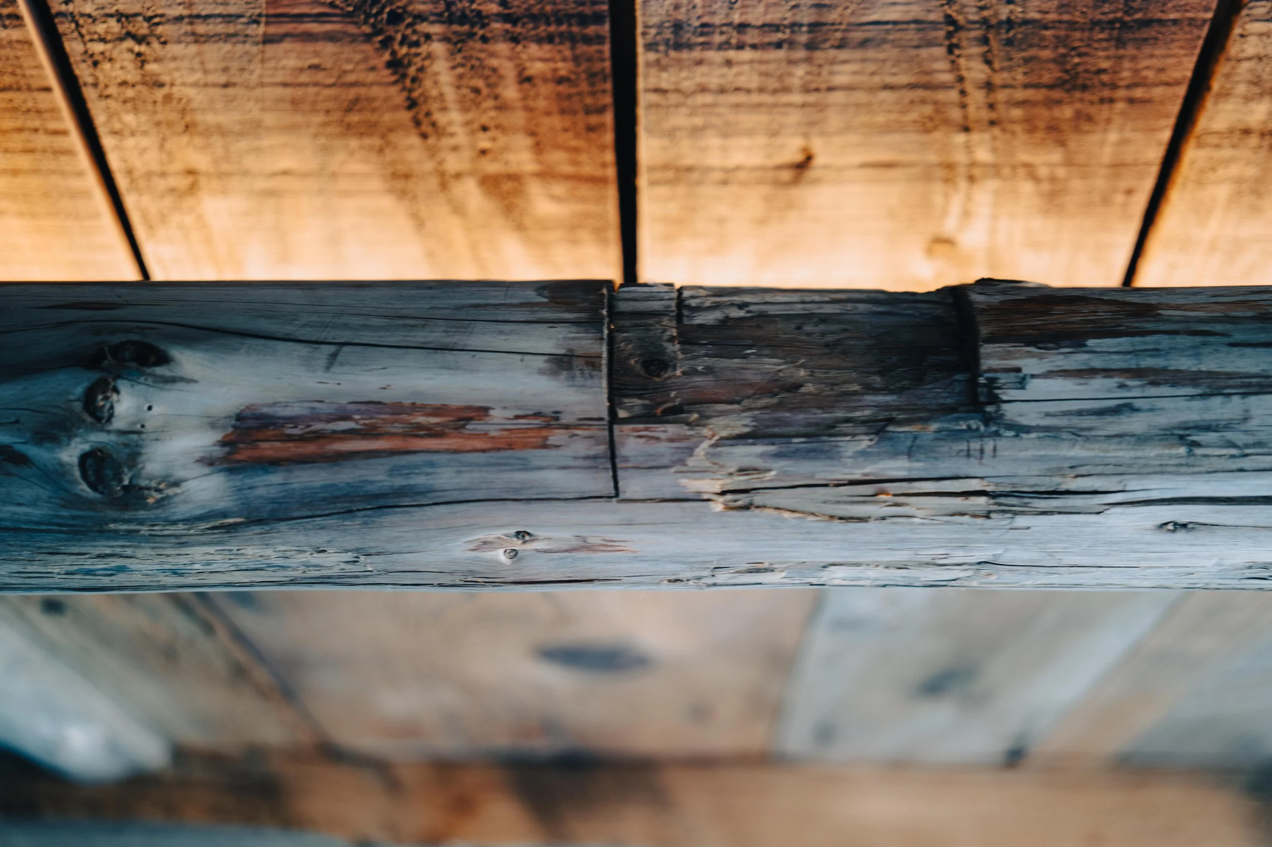 Close-up of weathered wooden beams, with a background of vertically aligned wooden planks.