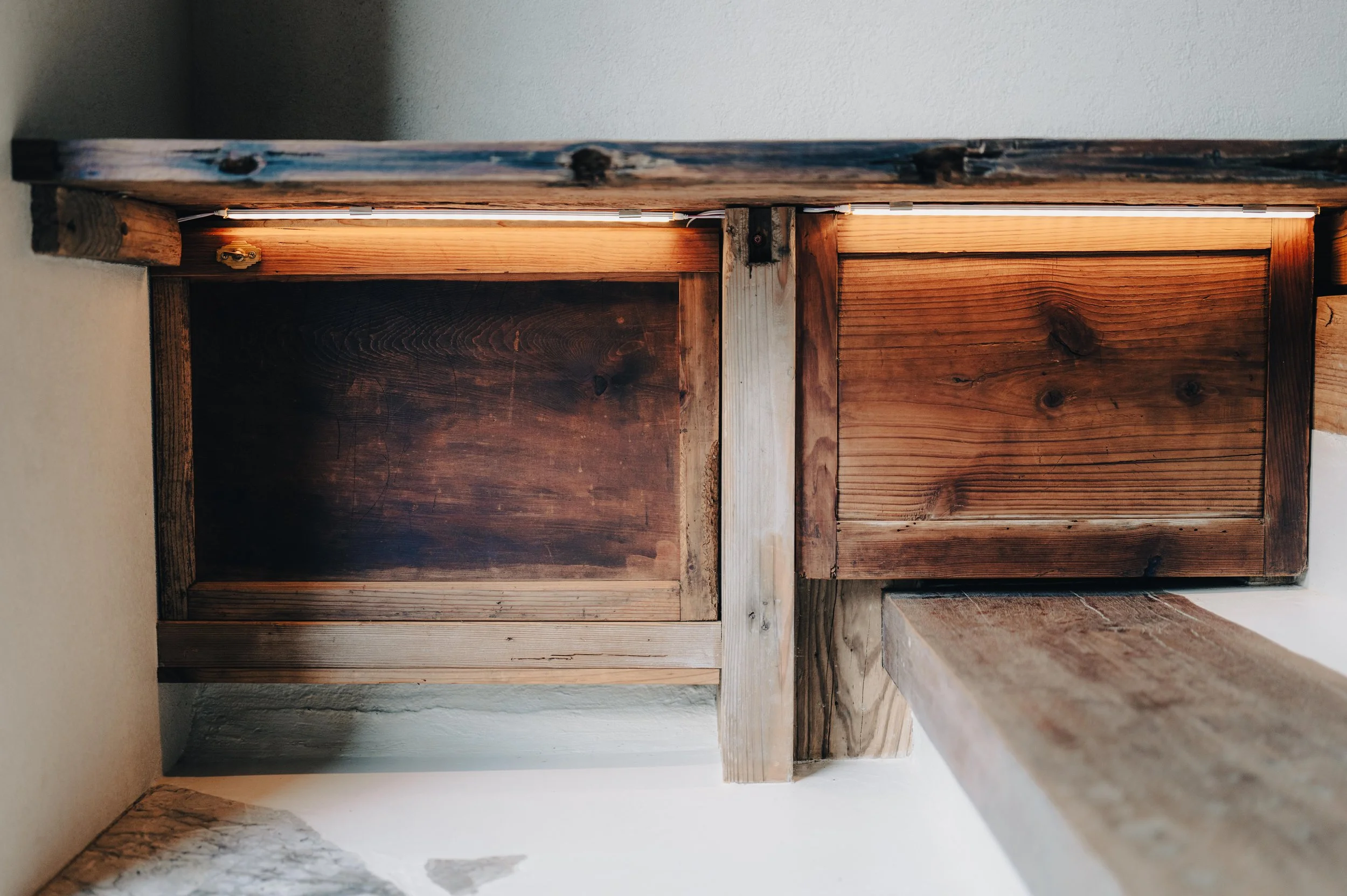 NUUT Aewol 눗애월 Close-up of a wooden structure with horizontal and vertical planks, showing natural wood grain and knots, with some light shining from above.