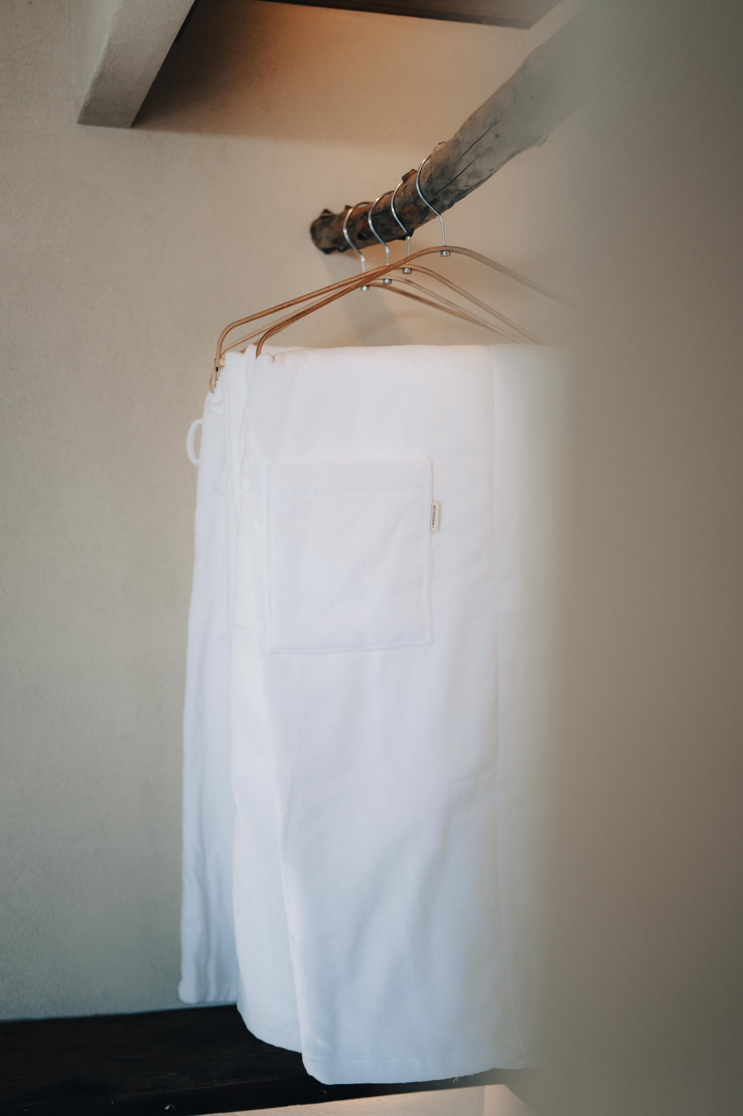 NUUT Aewol 눗애월 White laundry bag hanging on wooden hangers on a metal and wood clothes rod.