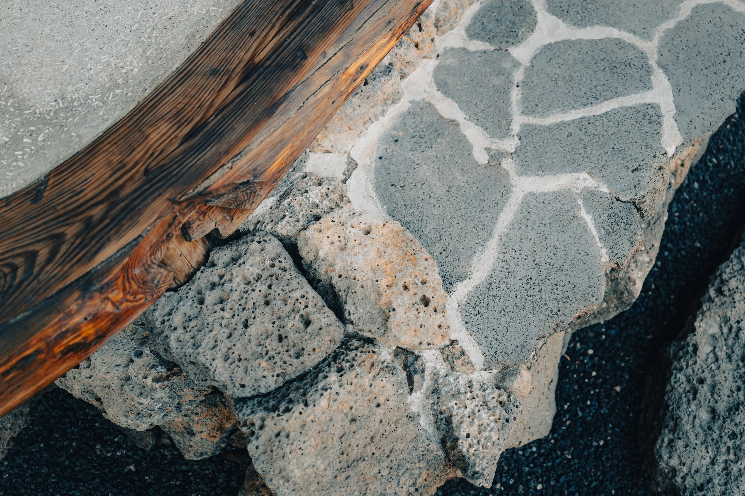 Close-up of layered stone and brick construction with a wooden beam.