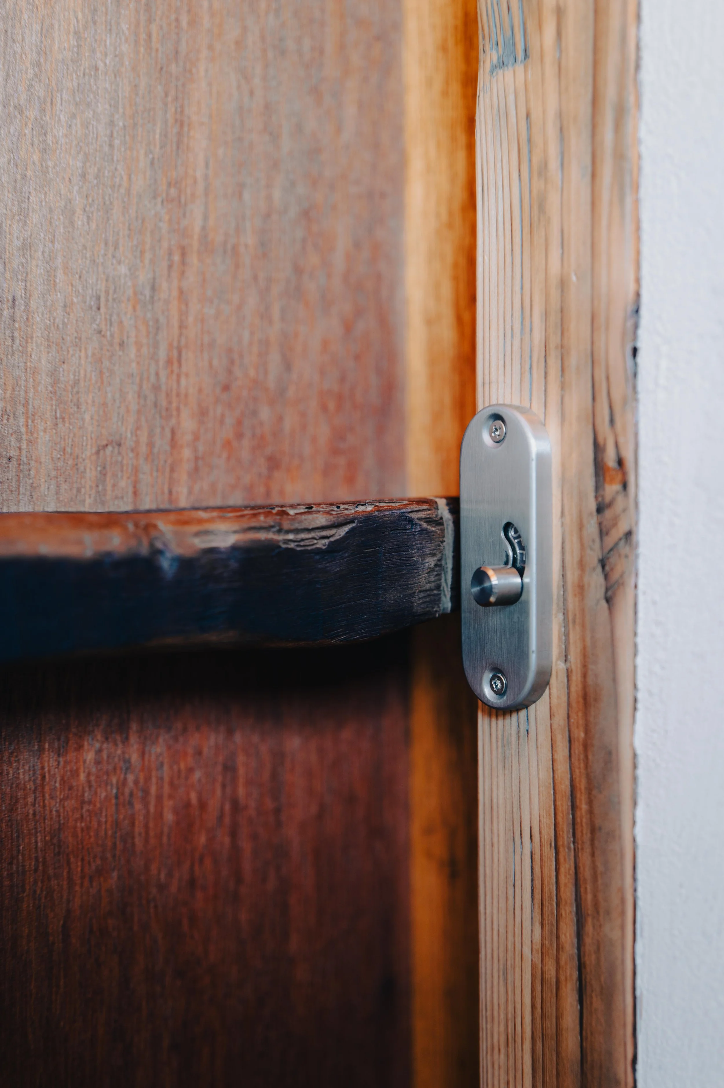 NUUT Aewol 눗애월 Close-up of a door latch on a wooden door, showing a metal latch mechanism.