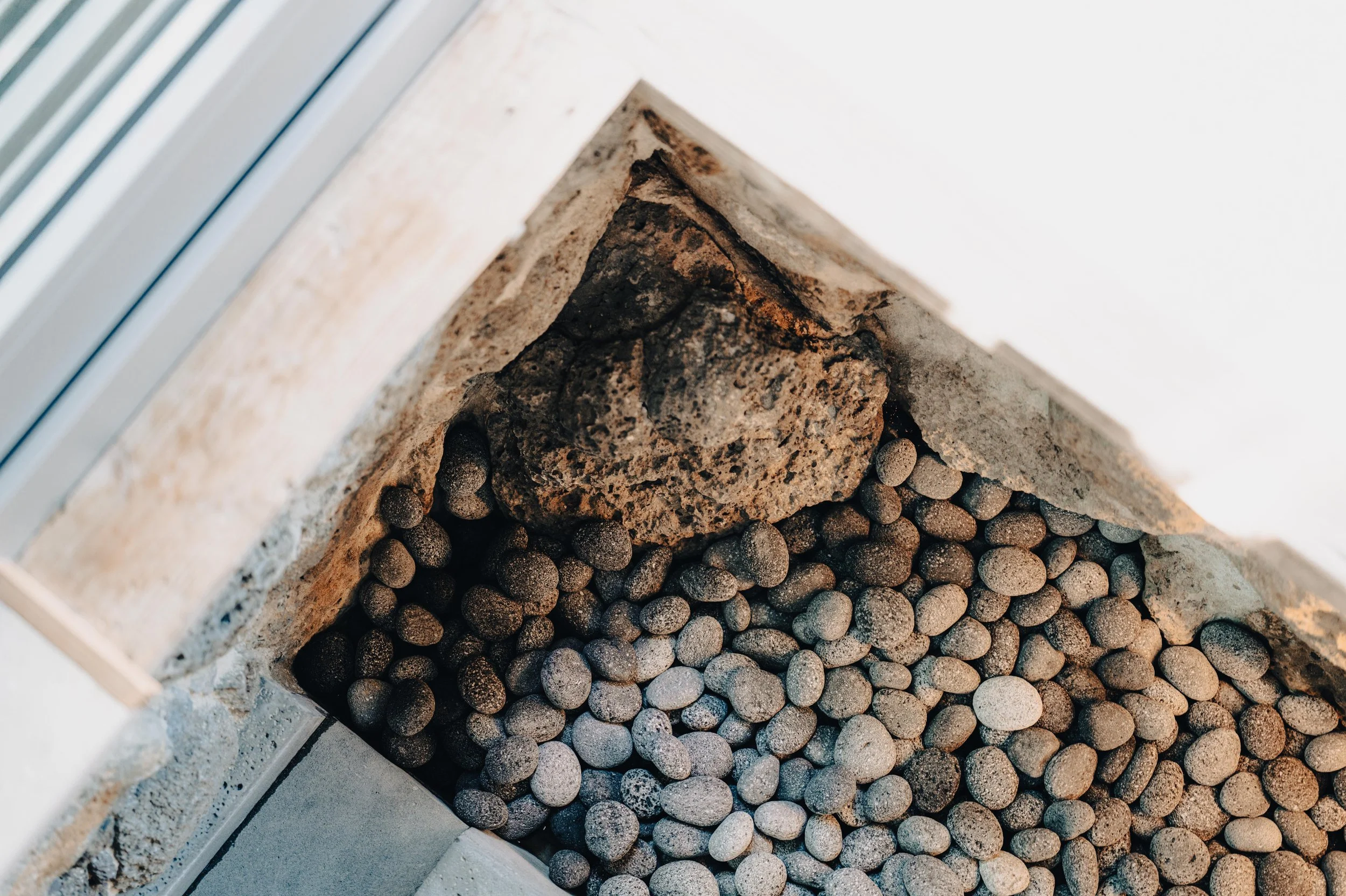 Close-up view of a brick corner filled with small round gravel stones and a larger irregular-shaped rock.
