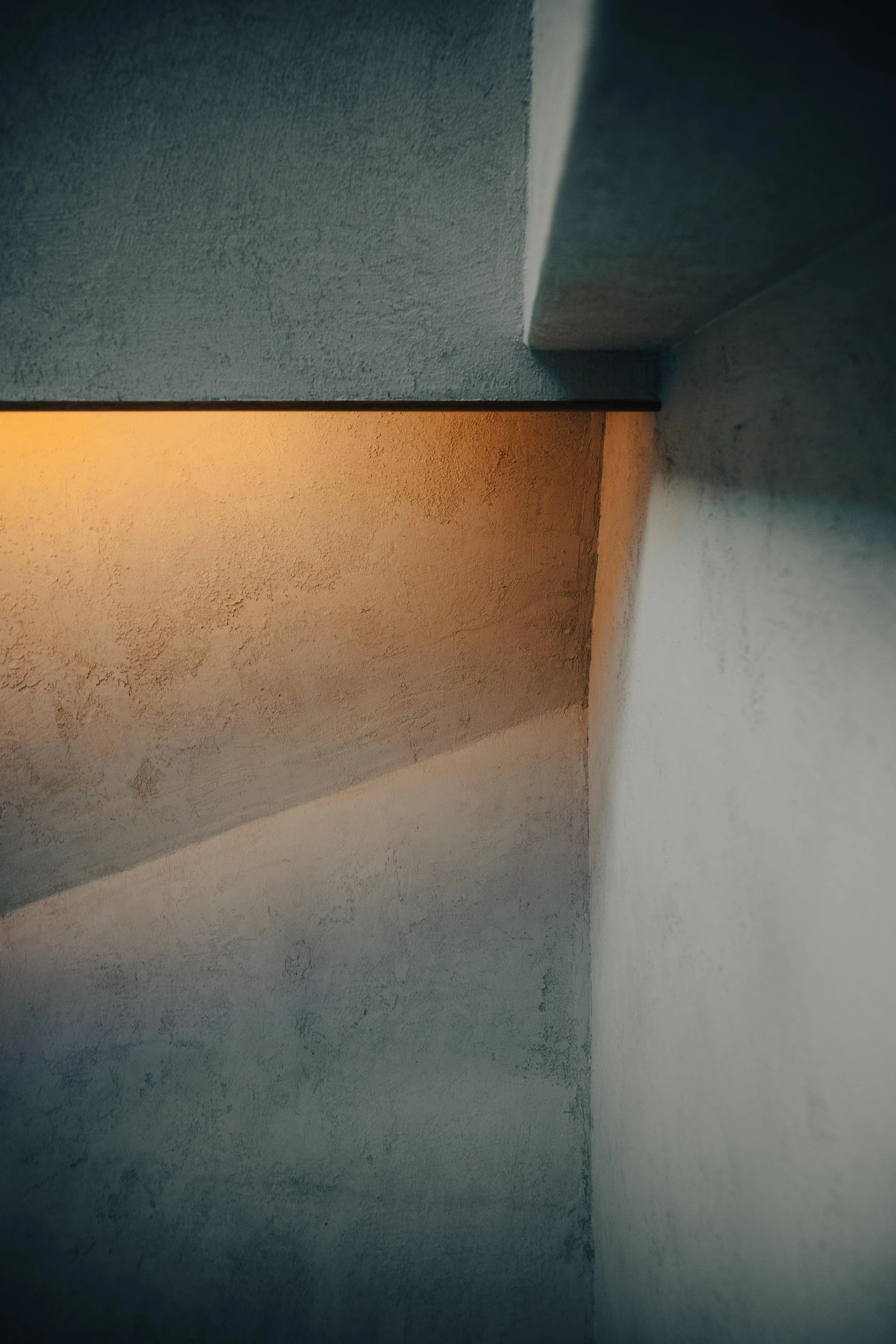 NUUT Aewol 눗애월 Close-up of a ceiling corner with textured walls and contrasting lighting.