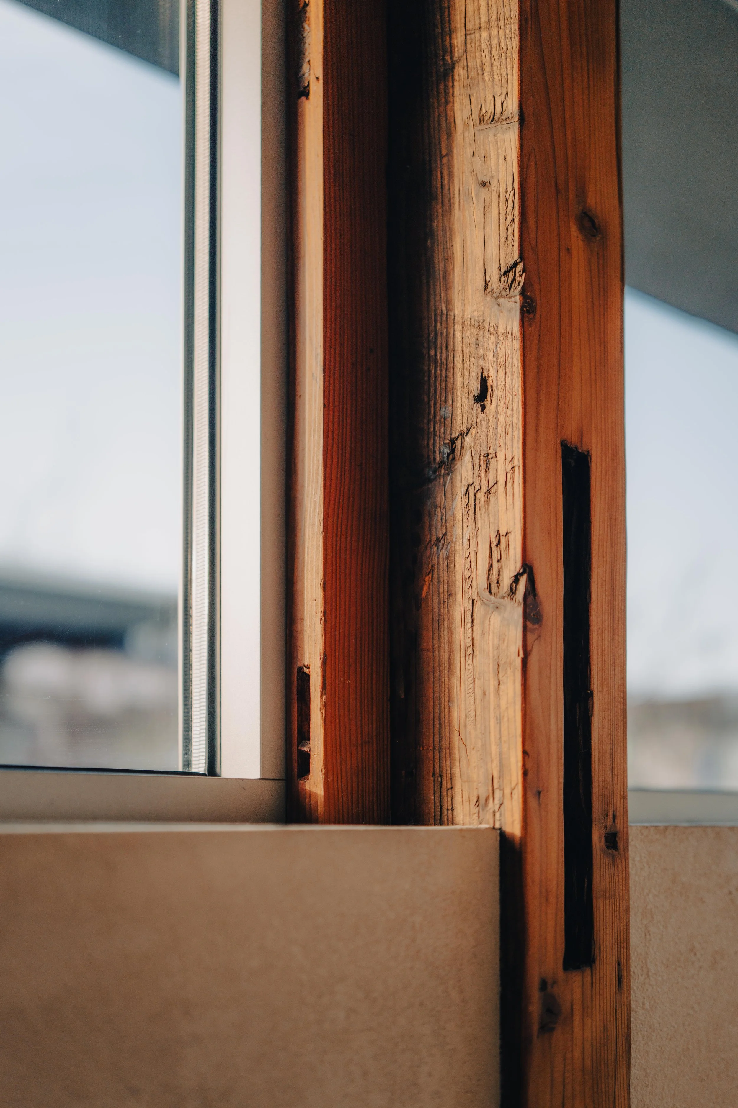 NUUT Aewol 눗애월 Close-up of a wooden window frame with visible wood grain and a glass window pane.