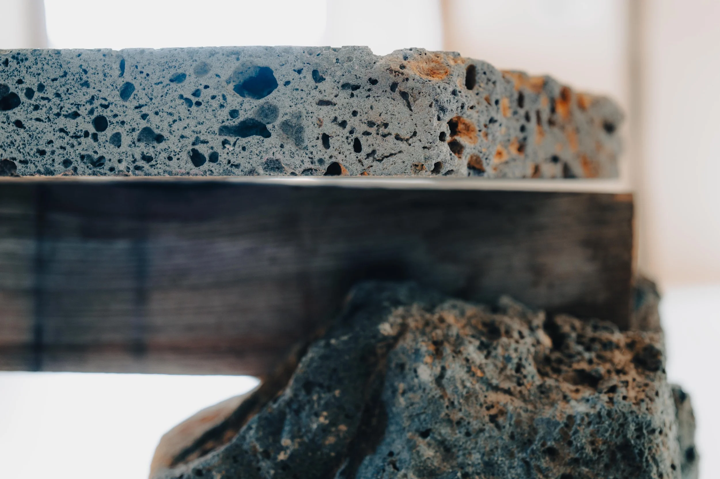 NUUT Aewol 눗애월 Close-up of a concrete slab above a wooden beam, supported by a rocky stone.