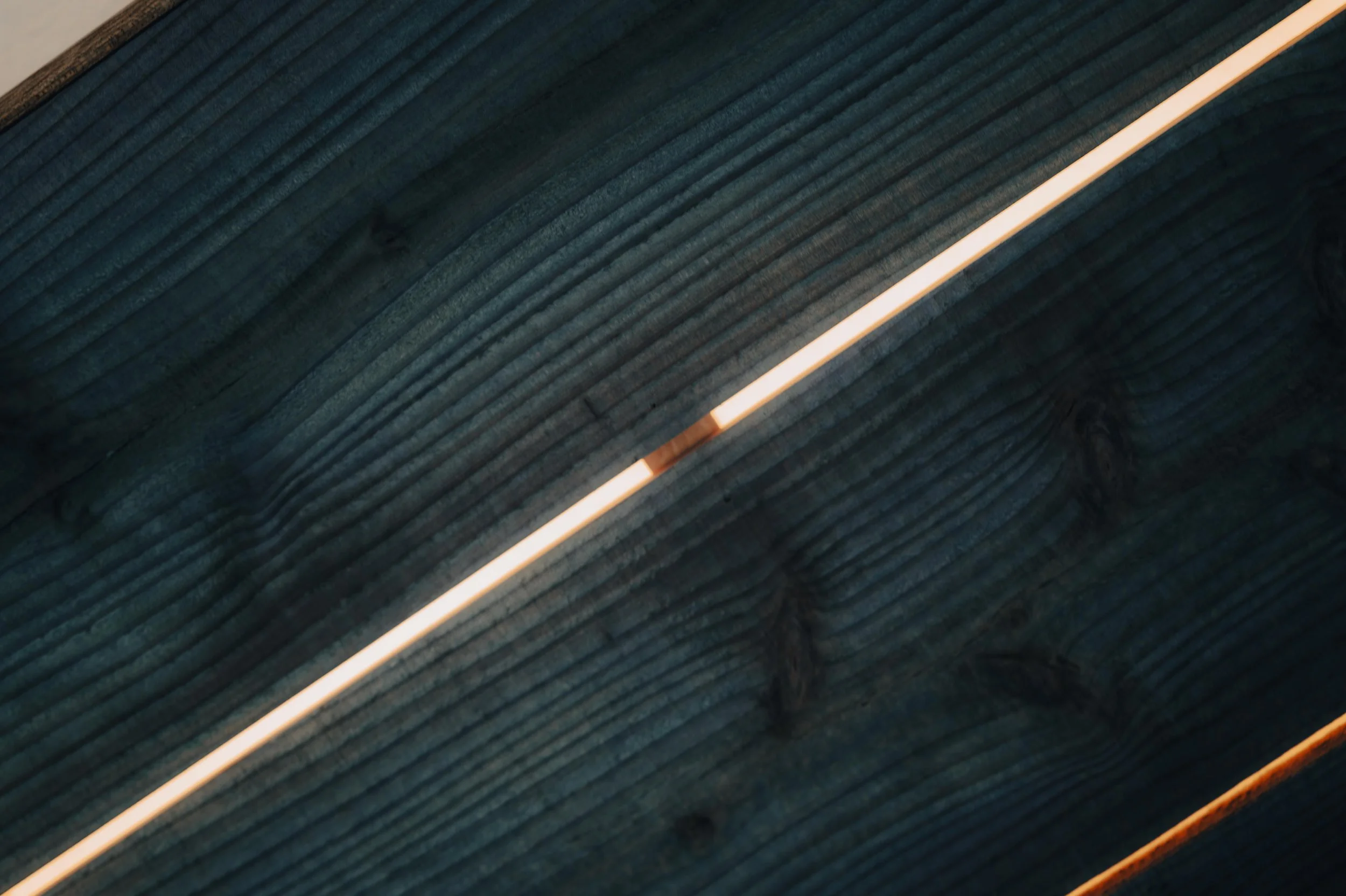 NUUT Aewol 눗애월 Close-up of wooden planks illuminated by LED strip light.