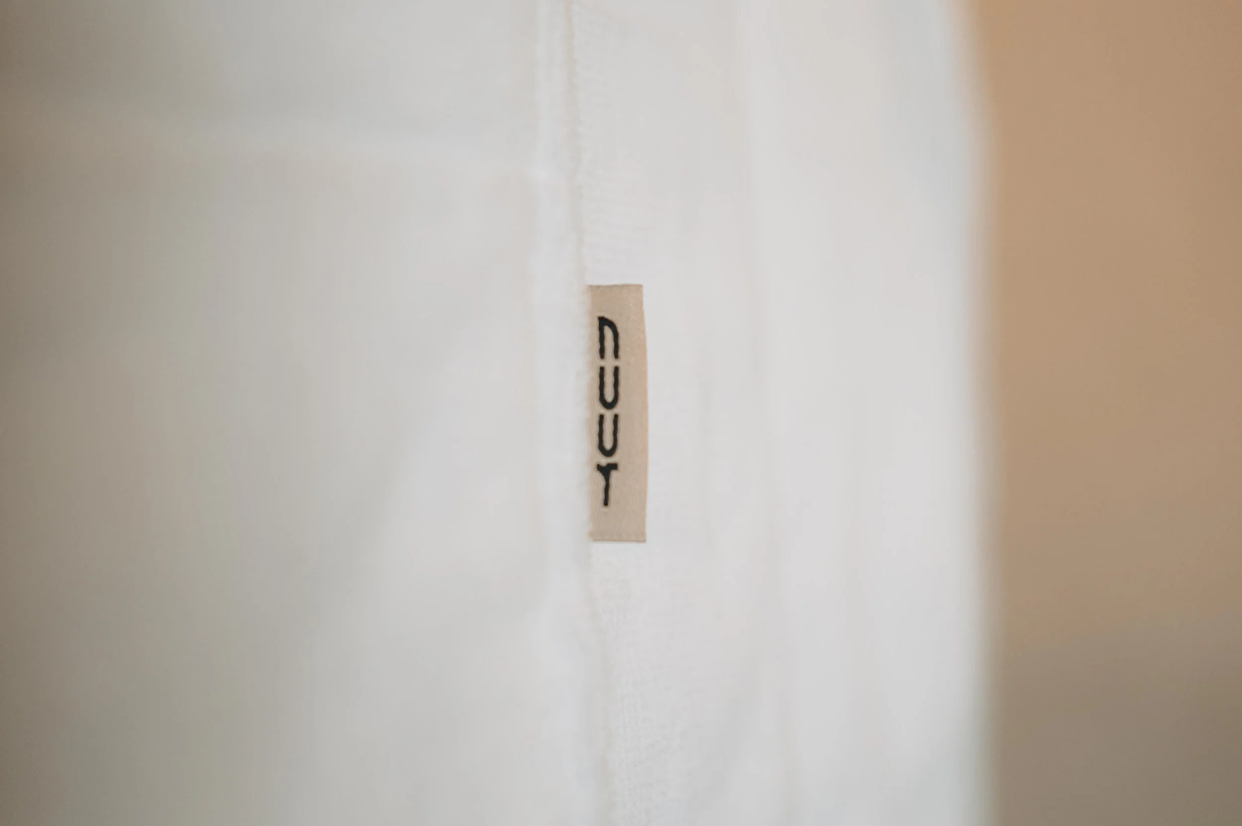 NUUT Aewol 눗애월 Close-up of a beige label with black text reading 'CICI' on a white fabric surface.