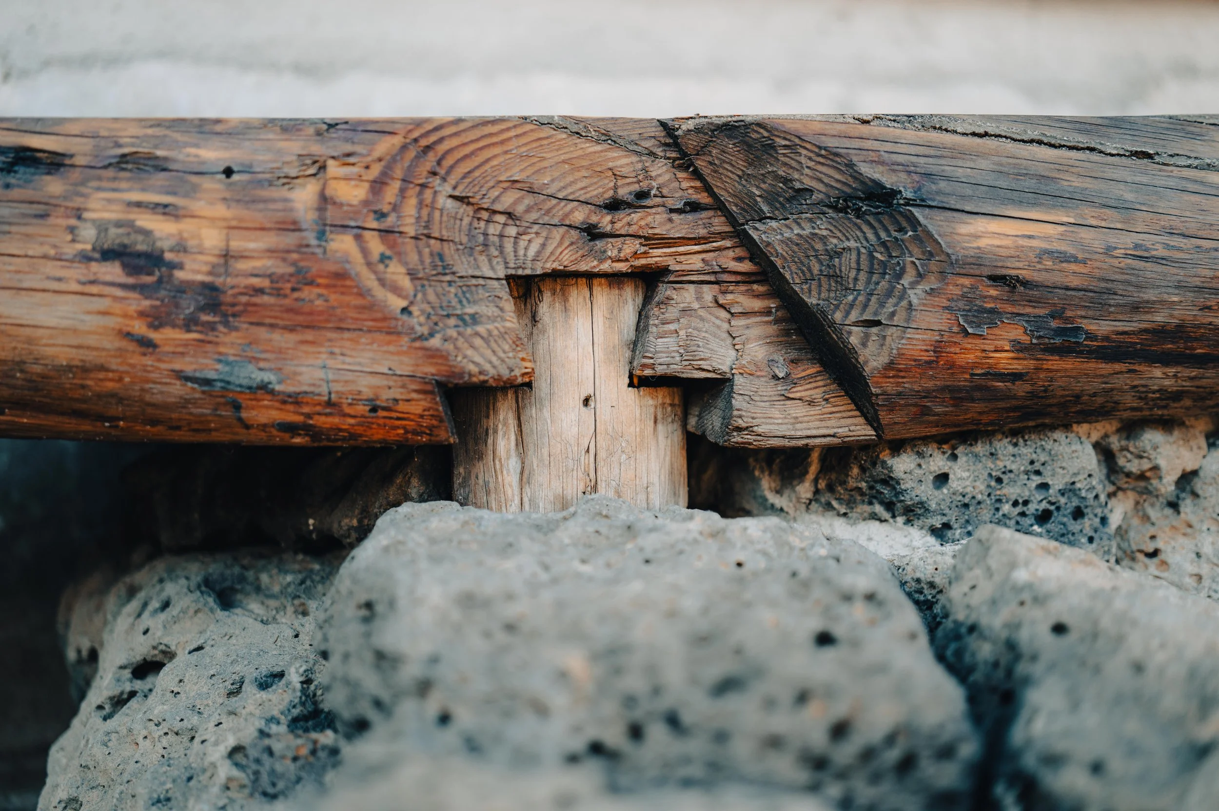 Close-up of weathered wooden logs and stones, with visible cracks and texture.