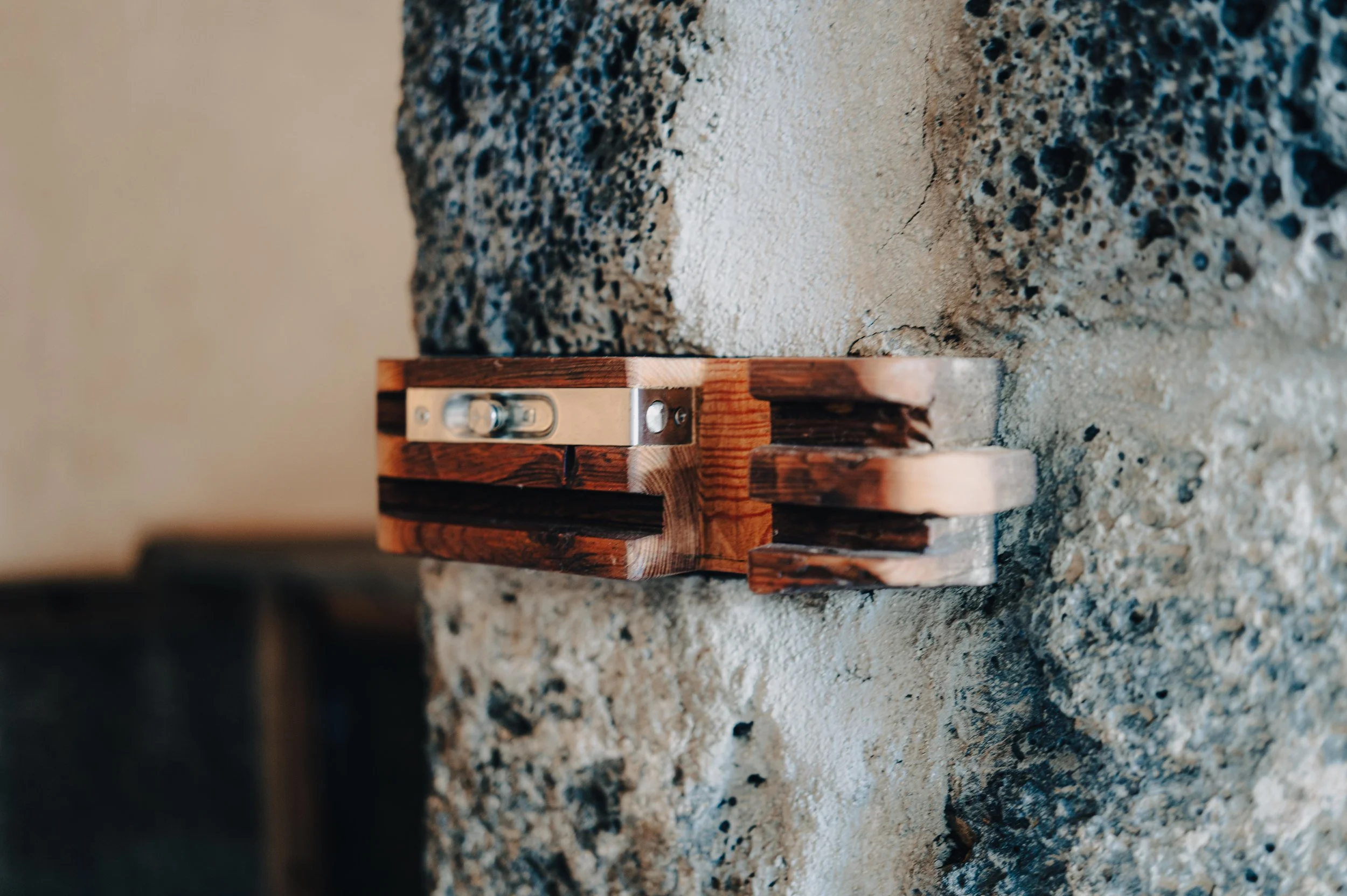 NUUT Aewol 눗애월 A small wooden level tool resting on a rough textured concrete and stone surface.