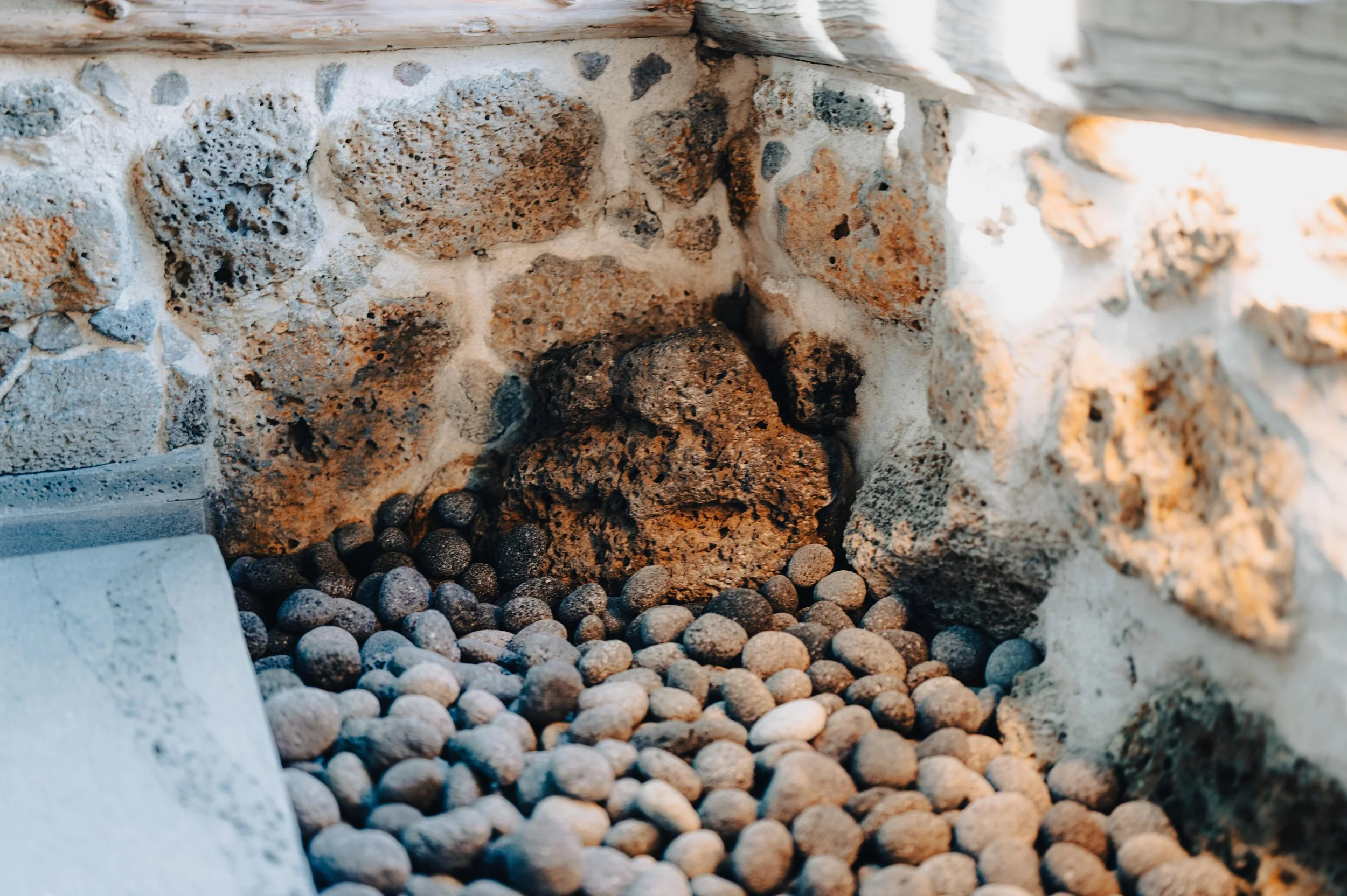 Close-up of a stone wall with a hole filled with small black and gray rocks.