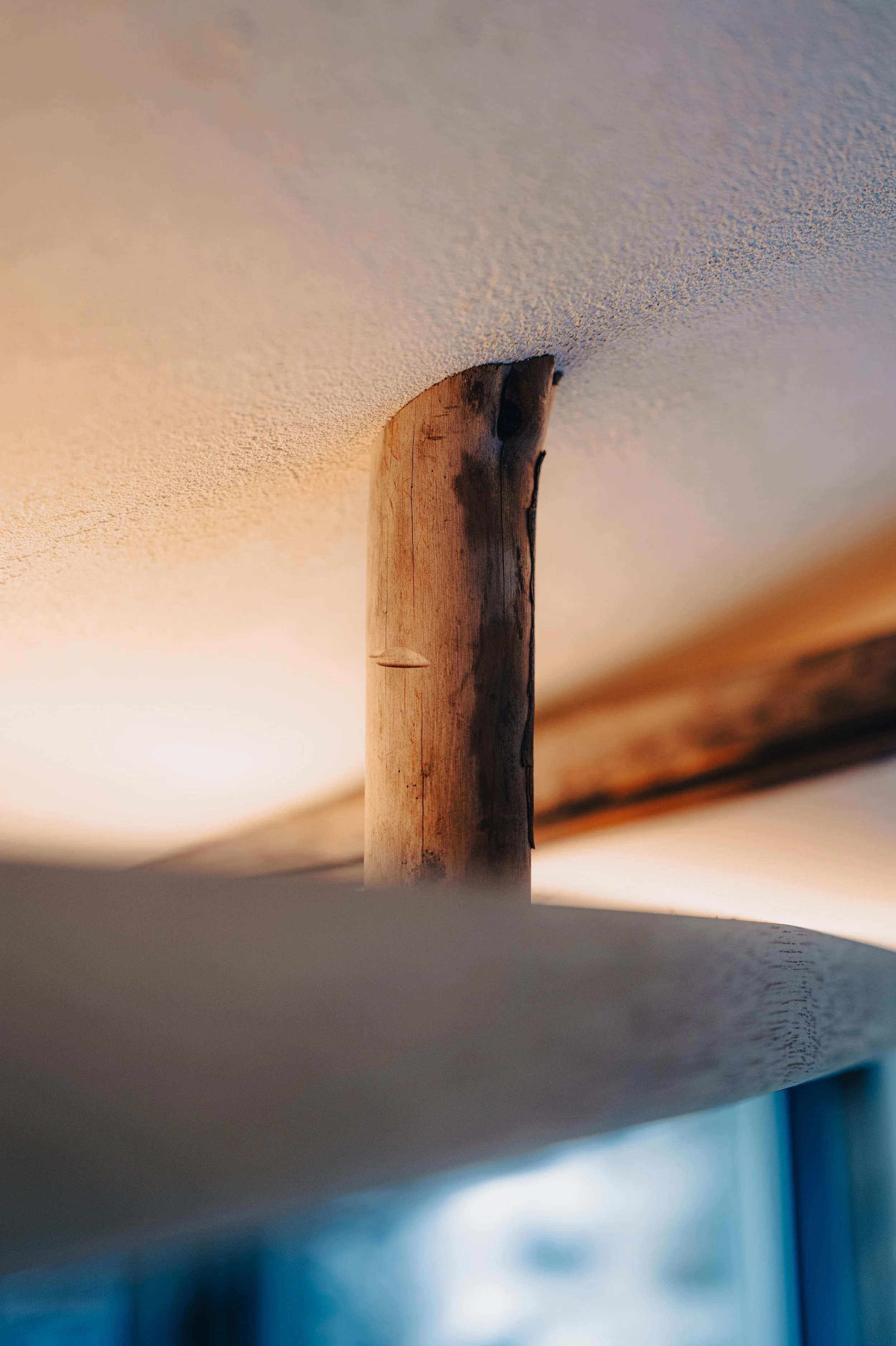 NUUT Aewol 눗애월 Close-up of a wooden support beam under a ceiling, with a blurred background.