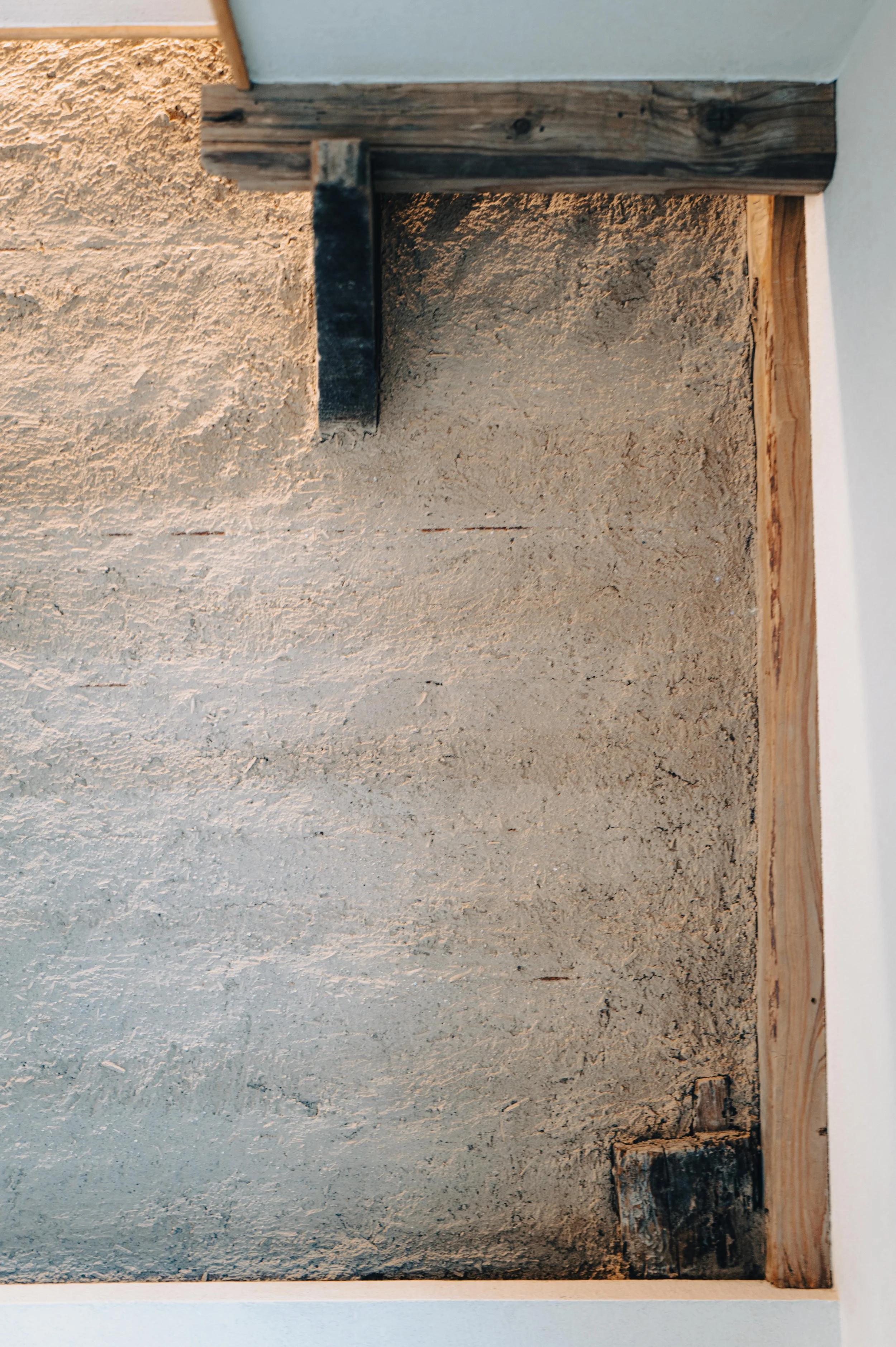 NUUT Aewol 눗애월 Close-up of a wooden frame with a textured beige wall inside it.