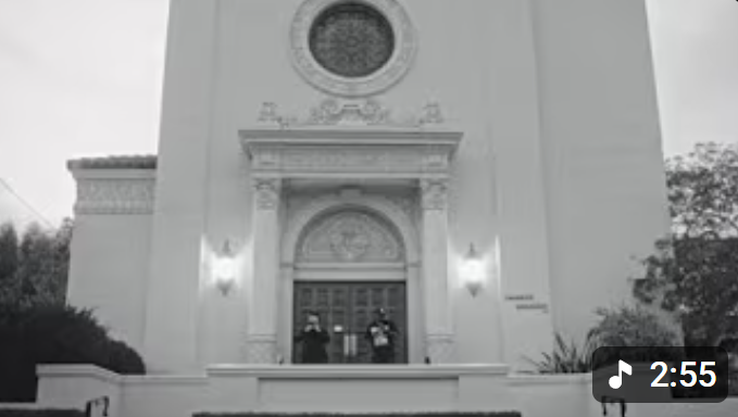 Black and white photo of a church or cathedral with two police officers standing at the entrance.