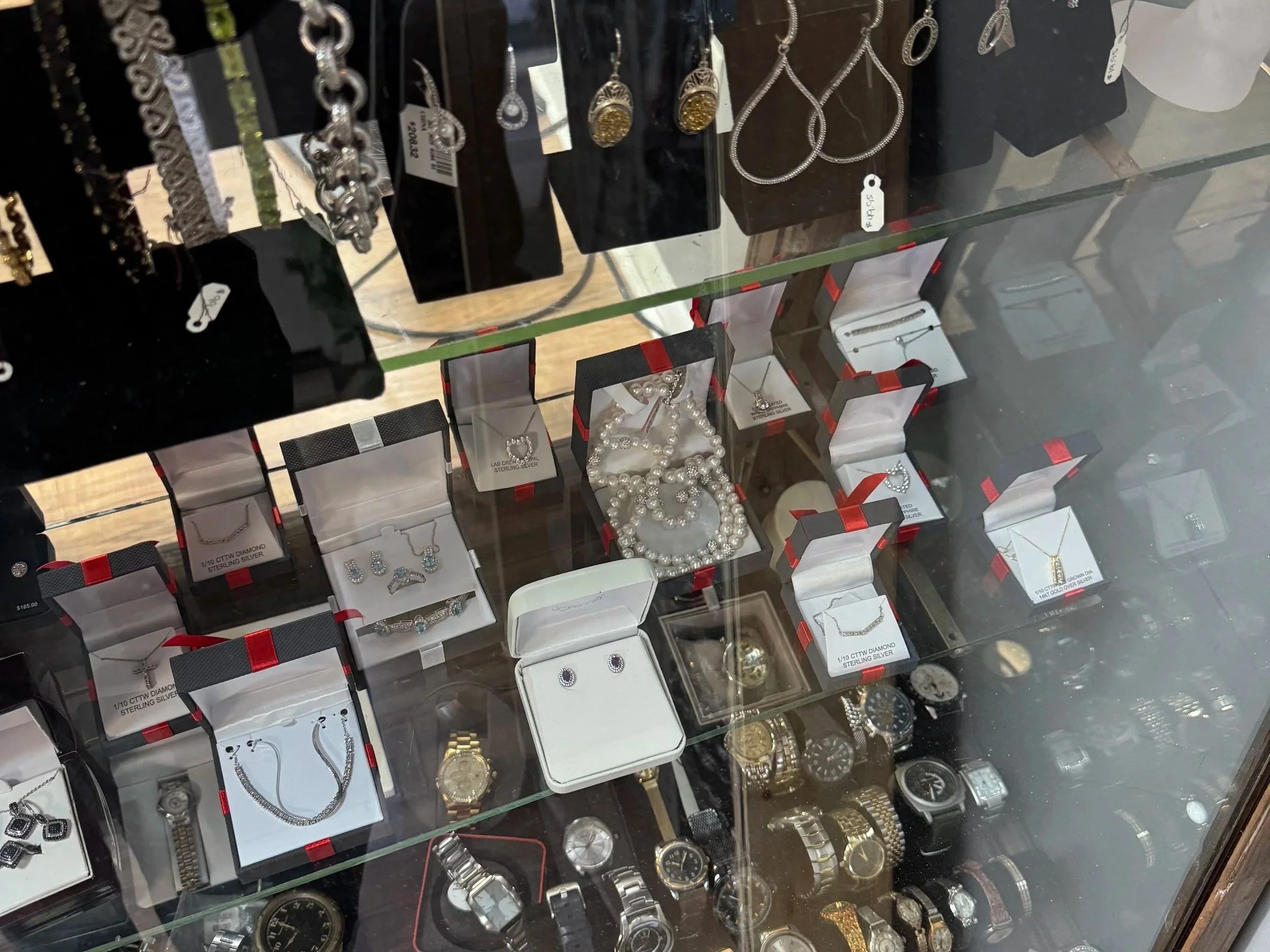 Jewelry display case with various necklaces, bracelets, earrings, and watches inside showcases.