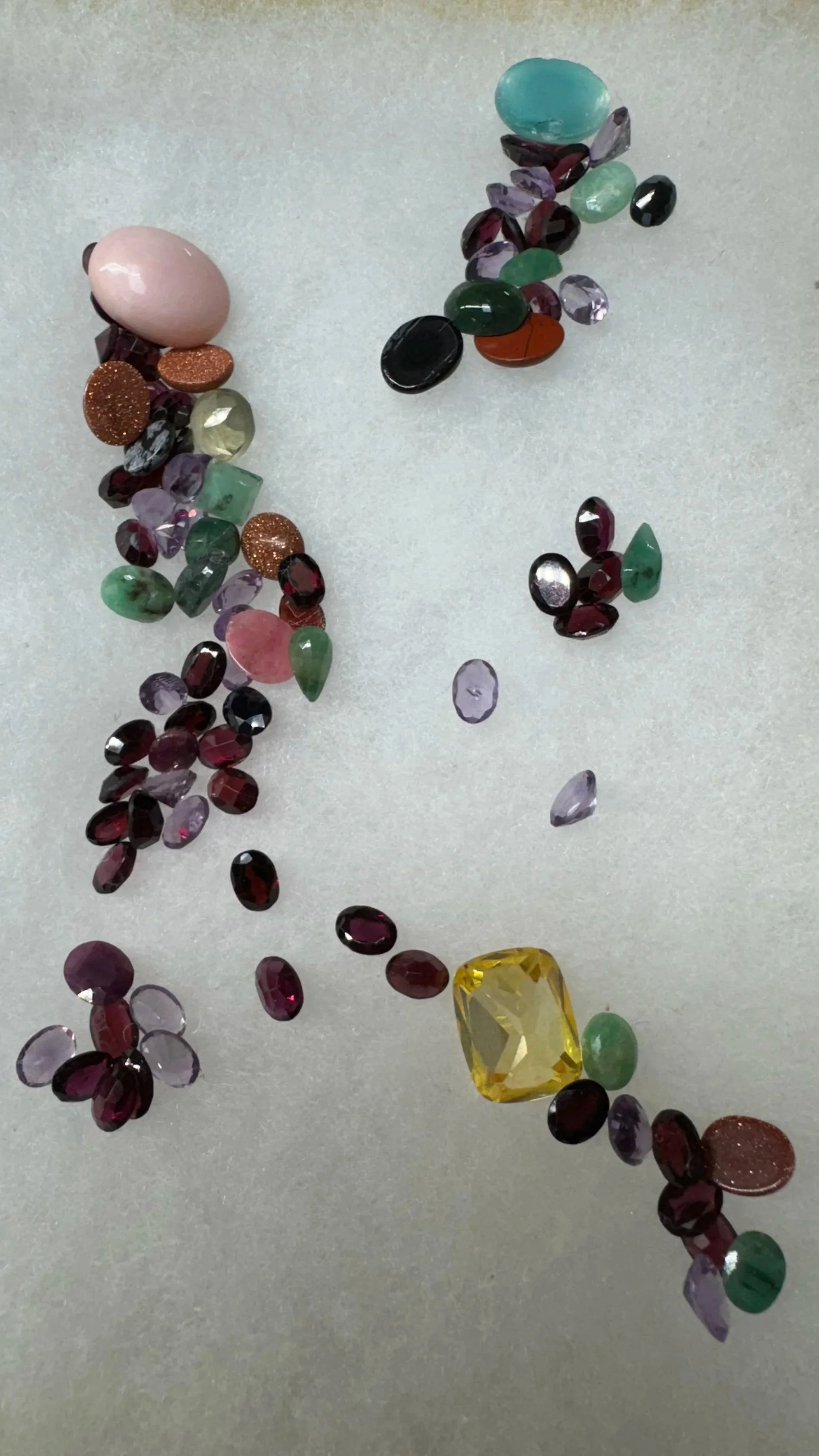 Various colorful gemstones arranged randomly on a light-colored surface.
