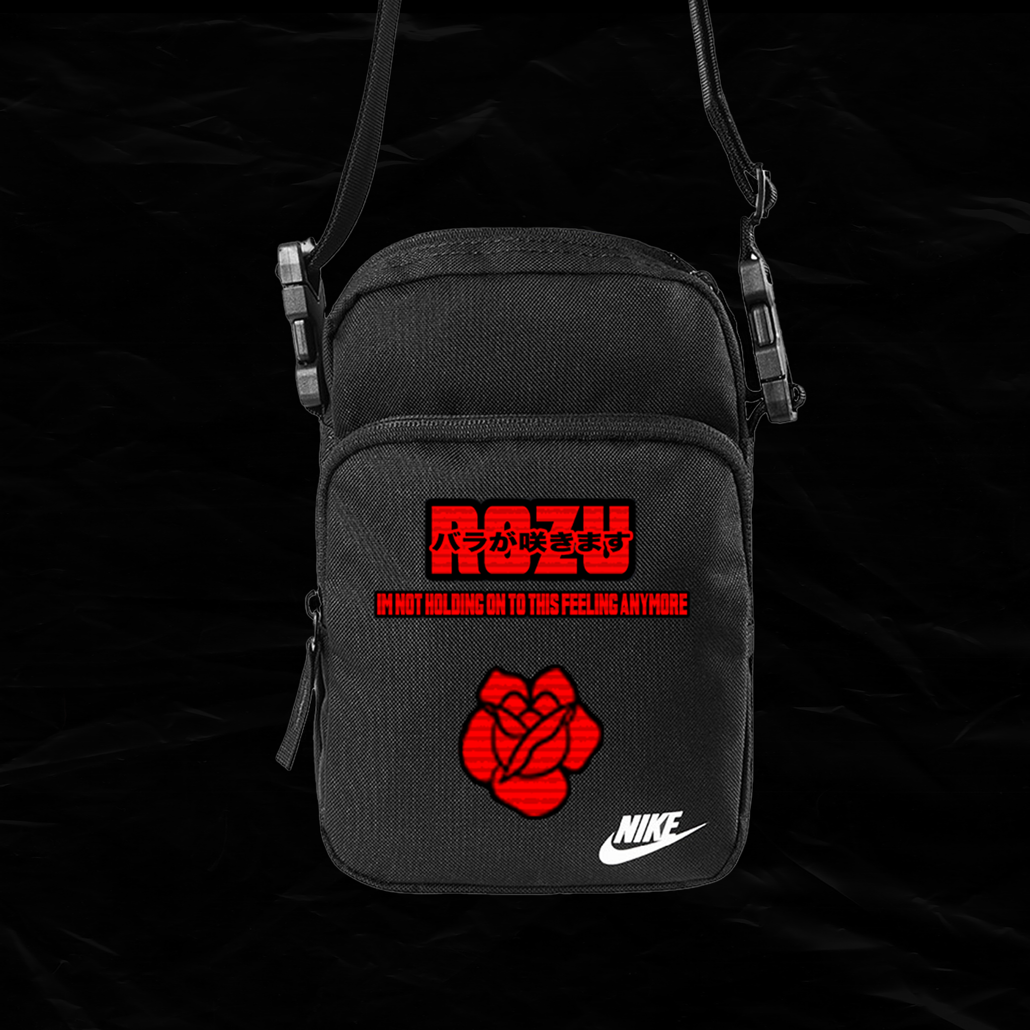 A black Nike shoulder bag with red and white text and graphics, including a sinking rose with the phrase "I am not holding on to this feeling anymore" and Japanese characters above the word "ROSE".