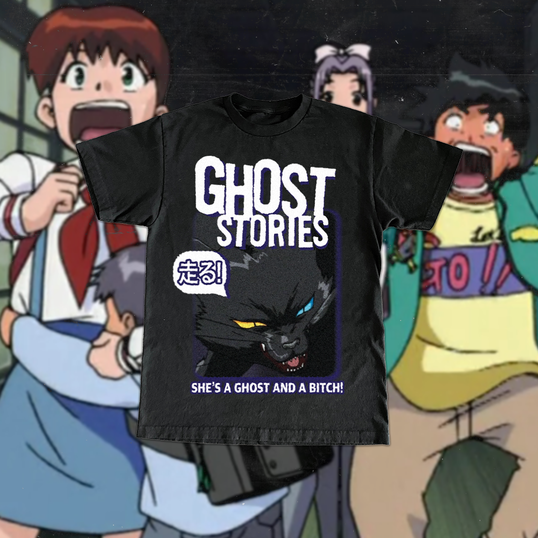 Black T-shirt with 'GHOST STORIES' text, a graphic of a black cat with heterochromatic eyes (yellow and blue), Japanese characters, and the phrase 'SHE'S A GHOST AND A BITCH!' displayed against a background of animated characters showing surprise.