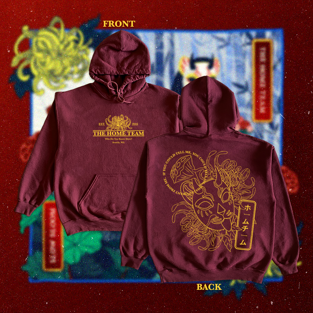 A maroon hoodie with front and back designs. The front has yellow text that reads 'EST 2016 THE HOME TEAM With Do You Know Here? Seattle, WA' and a graphic on top. The back features a large yellow line drawing of a lion's face with tribal elements an