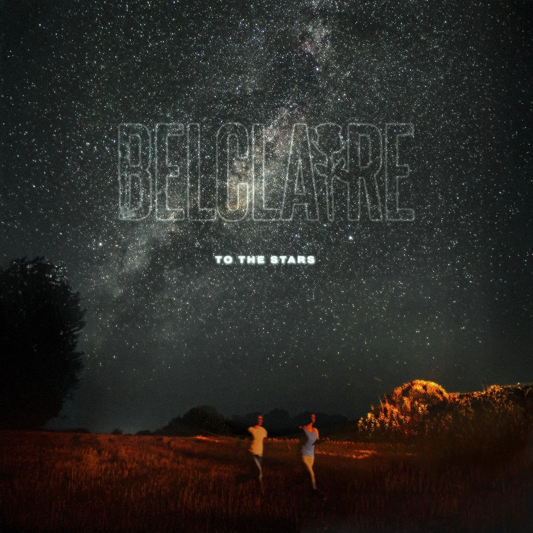 Two people standing in a grassy field beneath a starry night sky with the words 'BELIEVE TO THE STARS' faintly visible.