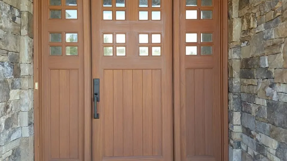 Wooden garage door with small square windows at the top, flanked by stone walls on both sides.