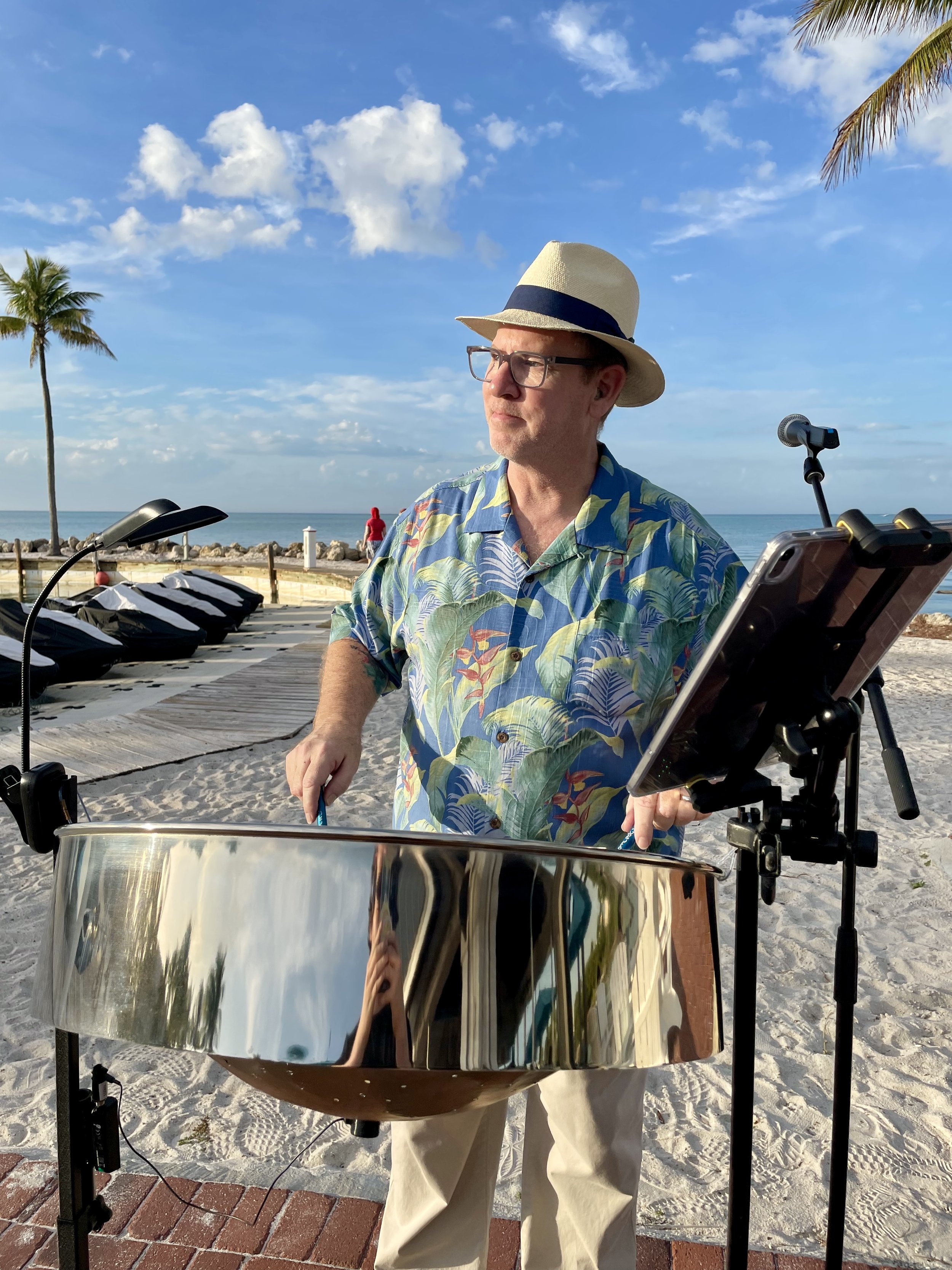 A man playing the steel drum on a beach with palm trees, sand, and the ocean in the background for a Resorts' residency, evening live music events, weekly. Tranquility Bay Beach Resort, Marathon Florida, Florida Keys.