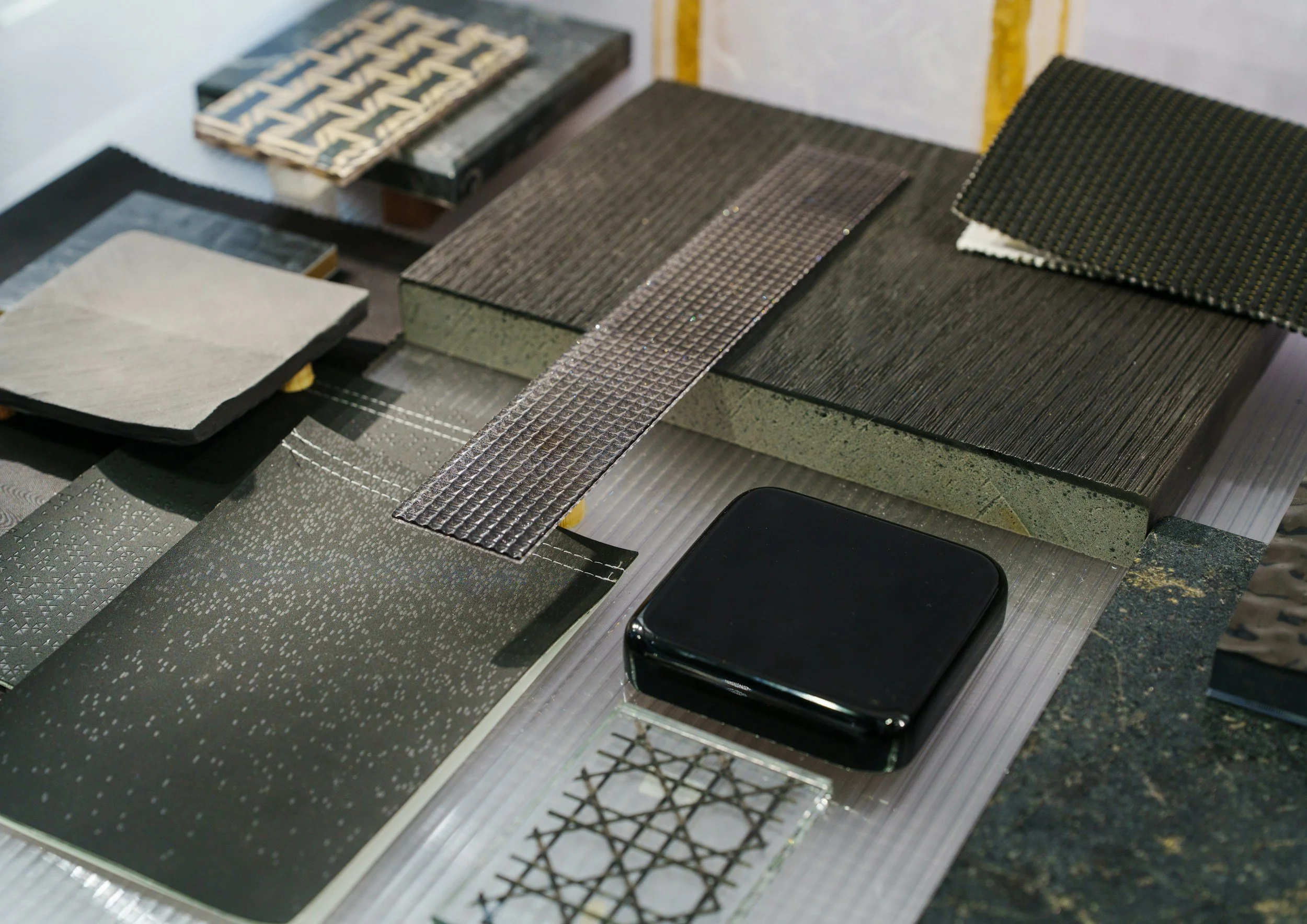 A variety of textured and patterned material samples, including tiles and electronic components, displayed on a table.