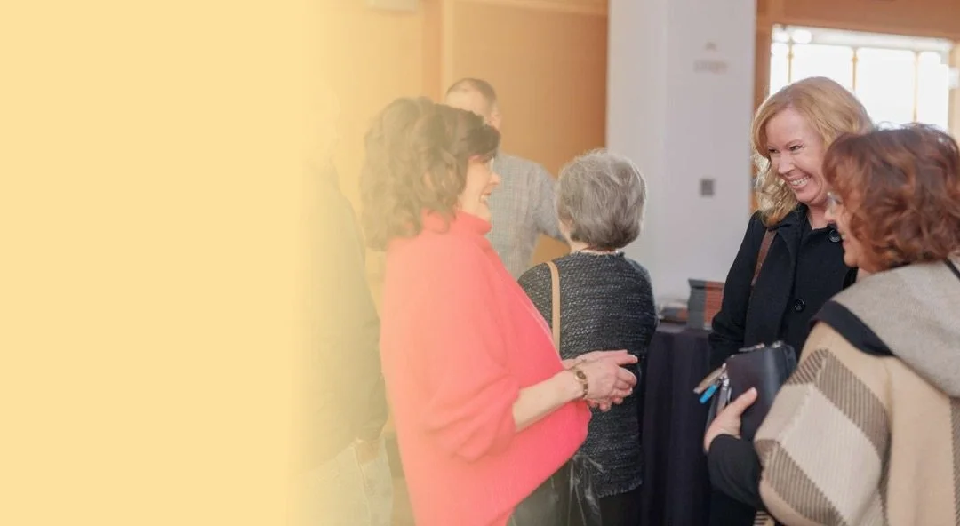 Group of women engaged in conversation indoors, smiling and chatting.