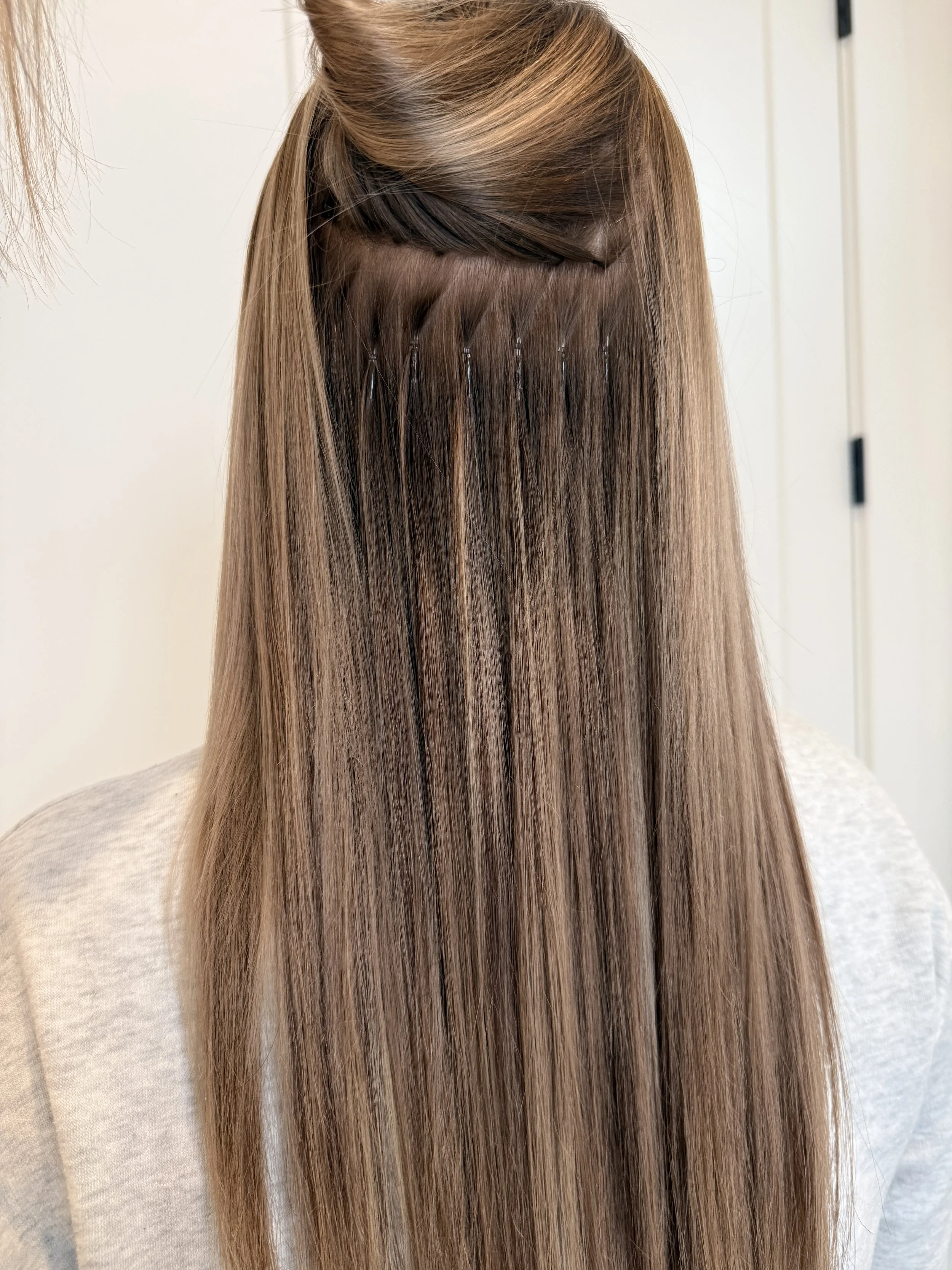 The image shows a close-up of a person's hair being straightened or treated, with hair clips securing sections of the hair, and the hair appears shiny and smooth.