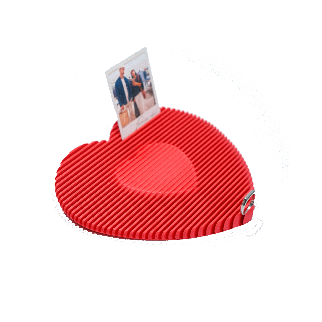 Red heart-shaped photo display frame with a small Polaroid photo of two people in the middle.