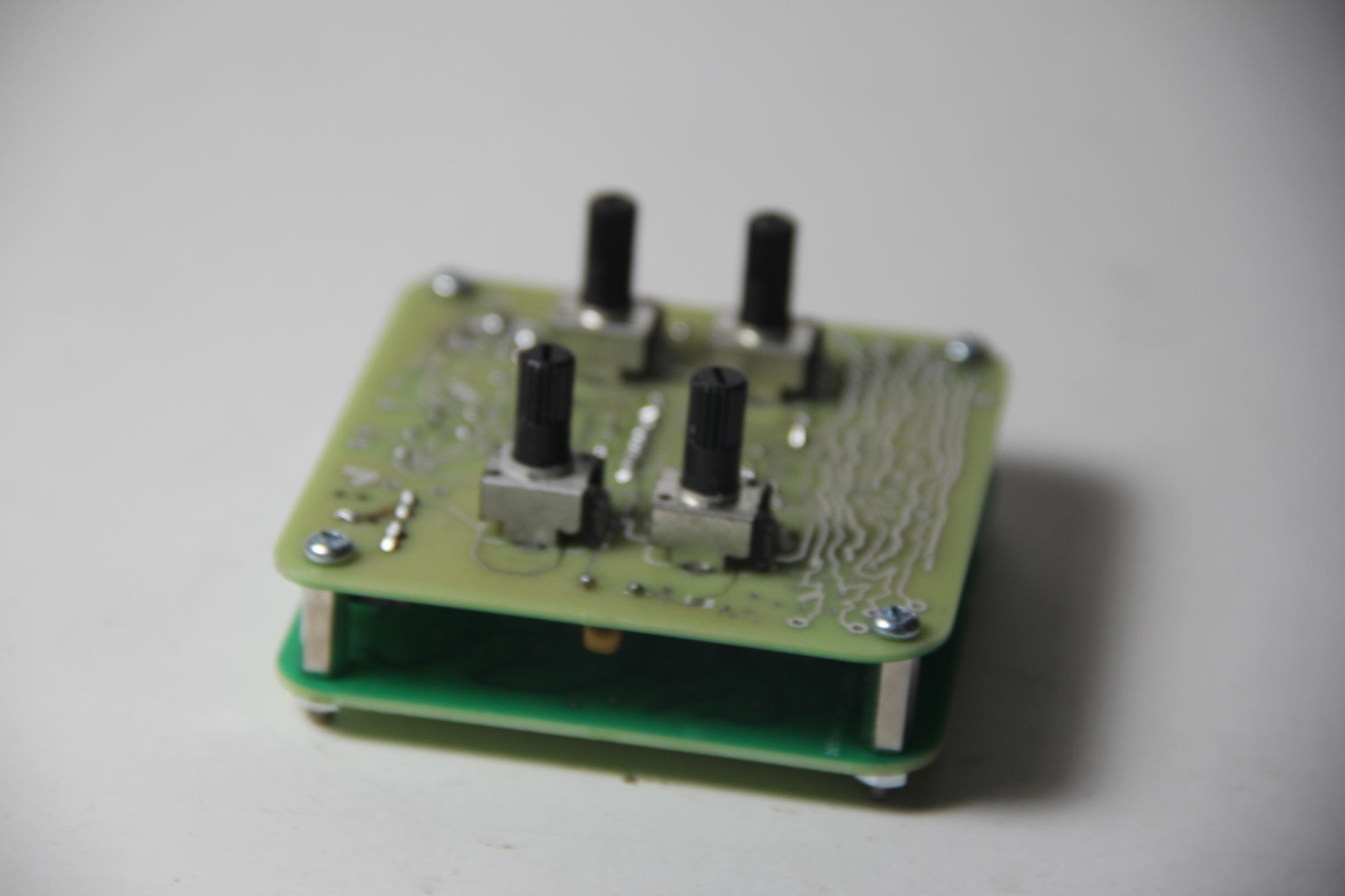 A close-up of a small electronic printed circuit board (PCB) with four black toggle switches mounted on it. The PCB has visible solder joints and traces, with the background blurred out.