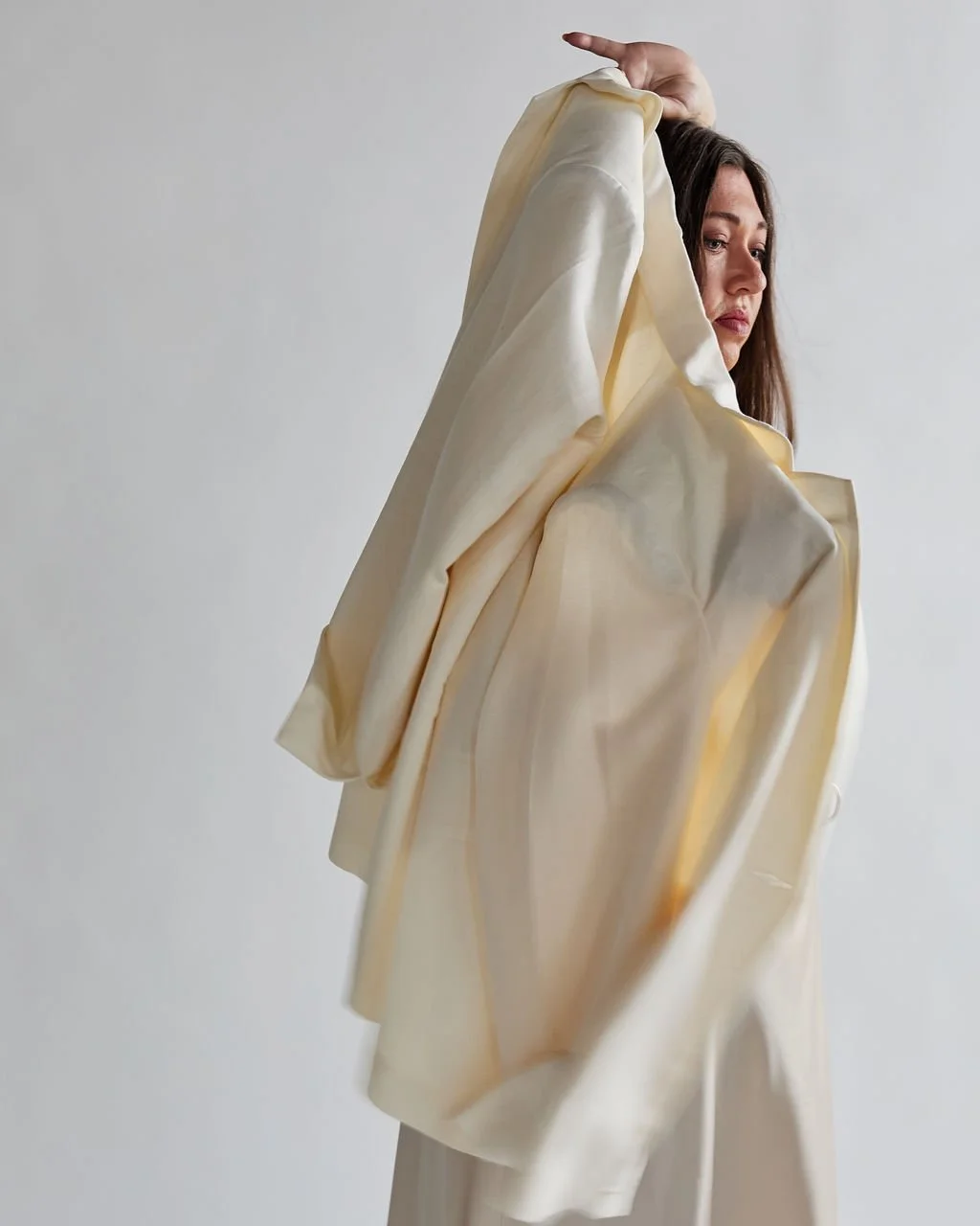 Tanya Jacobson, Capacity advisor that removes founder dependency and expands capacity for scaling founders, wearing an oversized, cream-colored, satin or silk coat, posing against a plain background.