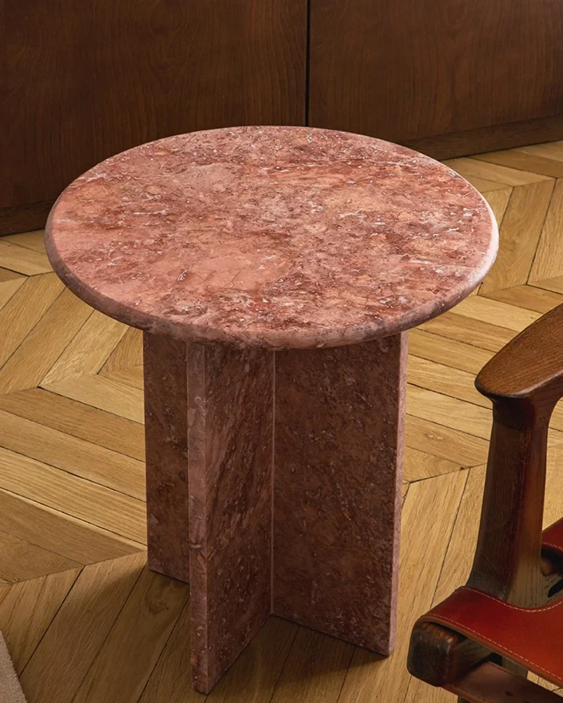 A round pink marble side table with a pedestal base.