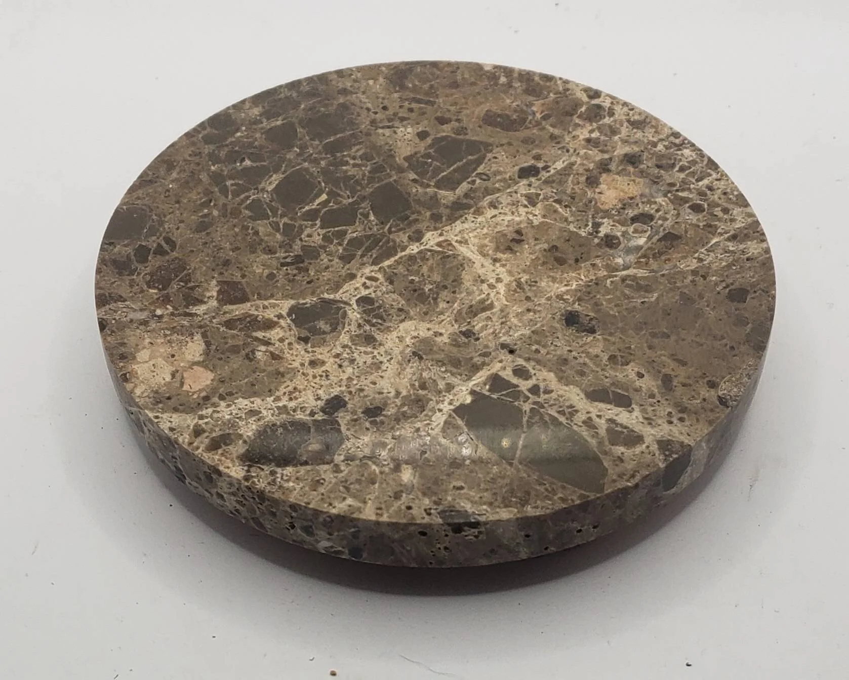 Round brown marble coaster with a polished surface showing a pattern of various brown, black, and beige veins and patches.