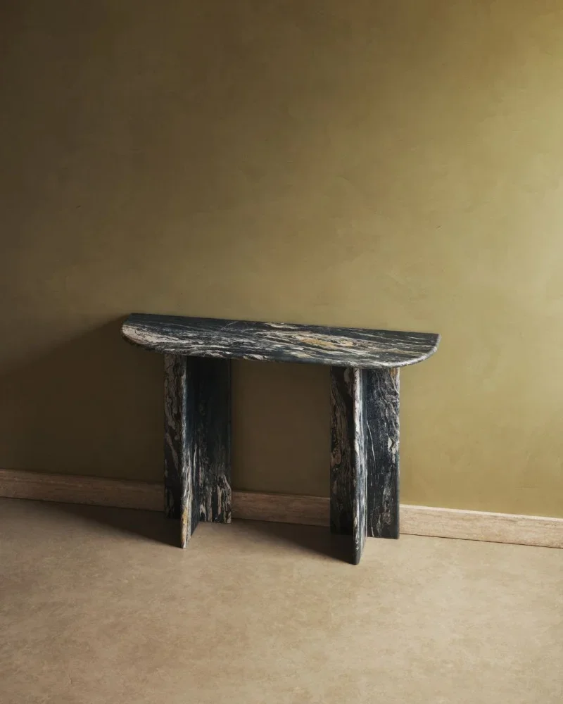 A blue dark marble table console table against a beige wall