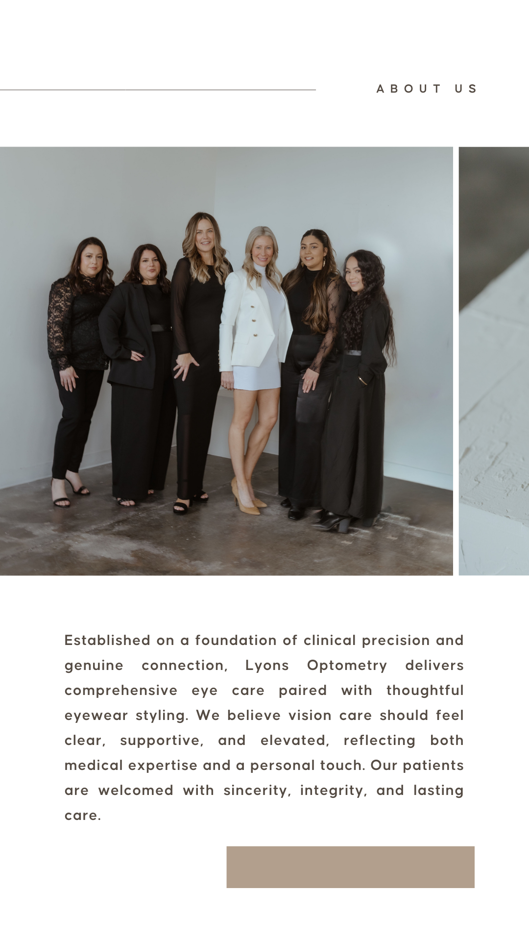 Group of six women standing together indoors, dressed in black and white professional attire, smiling at the camera.