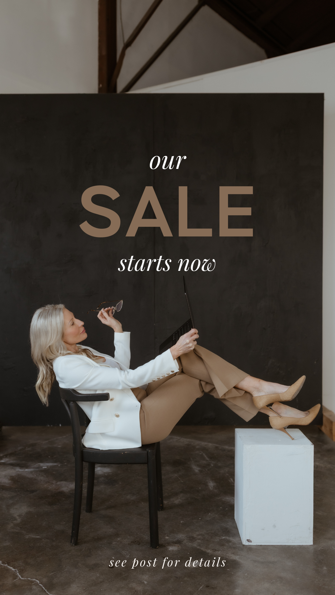 Woman sitting in a chair with legs on a white block, holding glasses and a laptop, promoting a sale starts now with a black background and text.