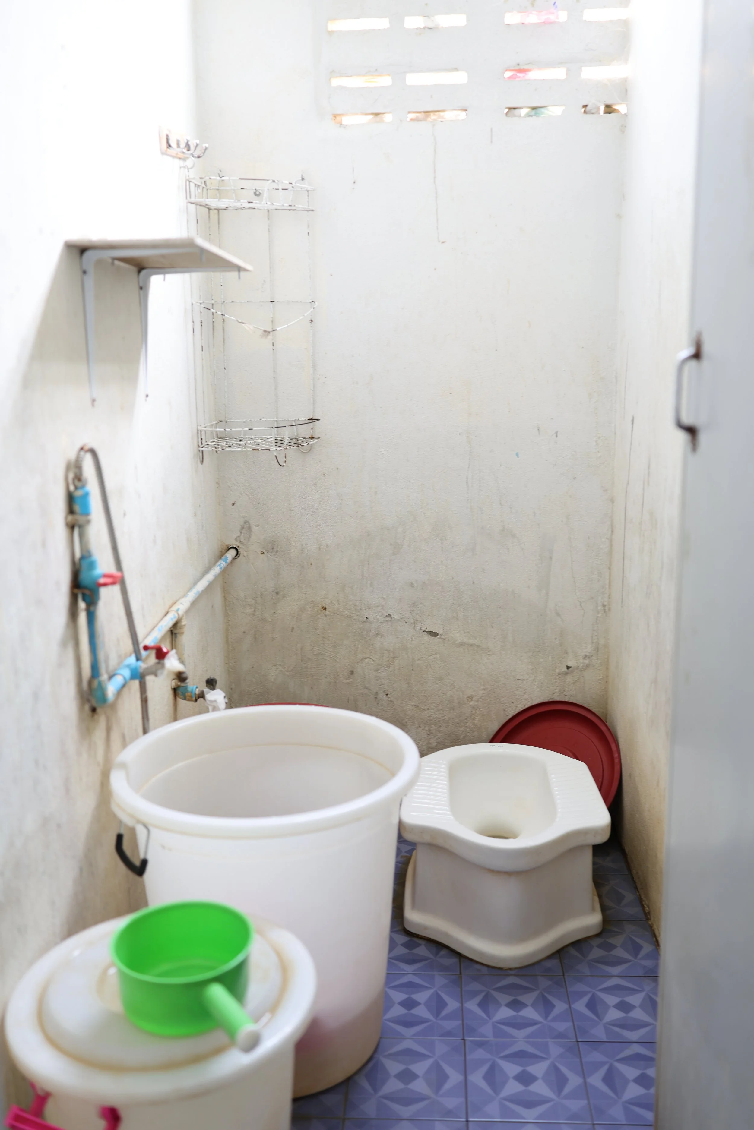 These are the original restroom facilities installed when the dormitory was first constructed more than 35 years ago. The toilets do not have flushing systems, requiring the girls to manually flush using buckets of water. With only five toilets servi