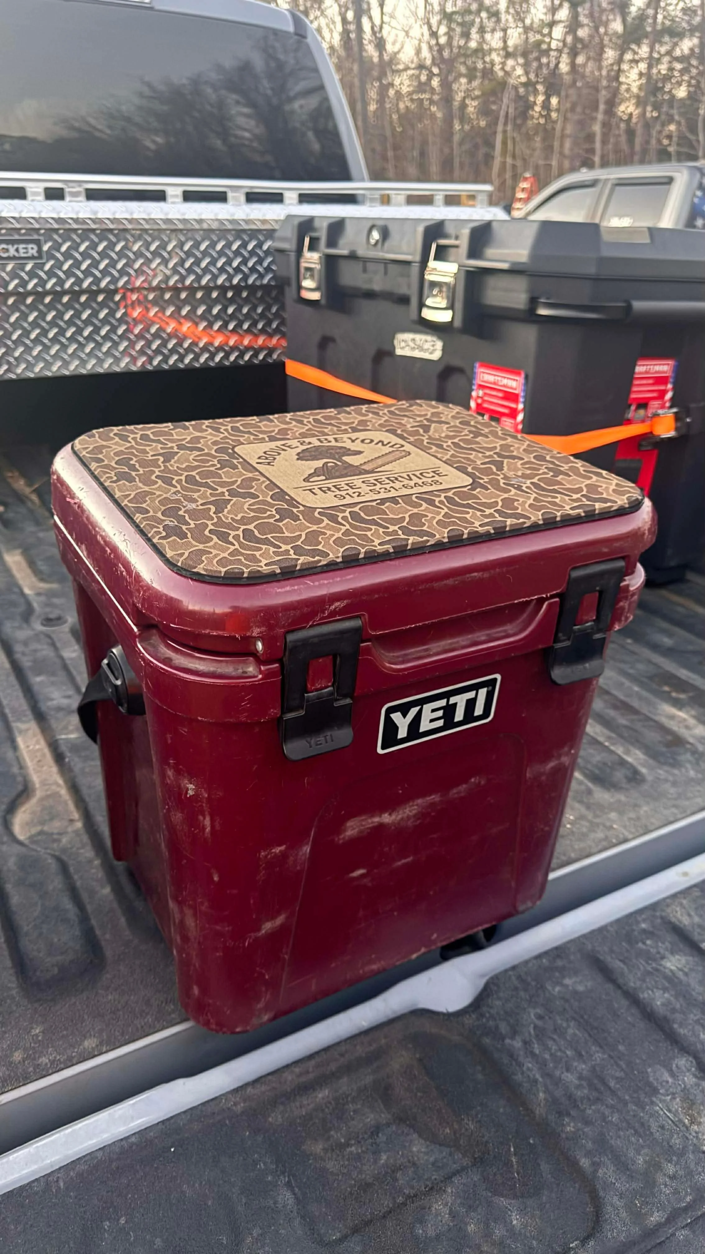 A red Yeti cooler in a pickup truck bed with other storage containers behind it.