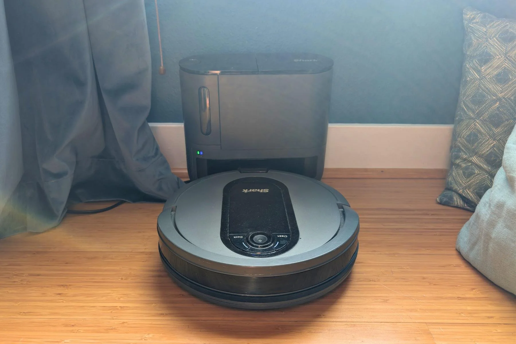 Shark EZ Robot Vacuum docked on self-empty base on hardwood floor