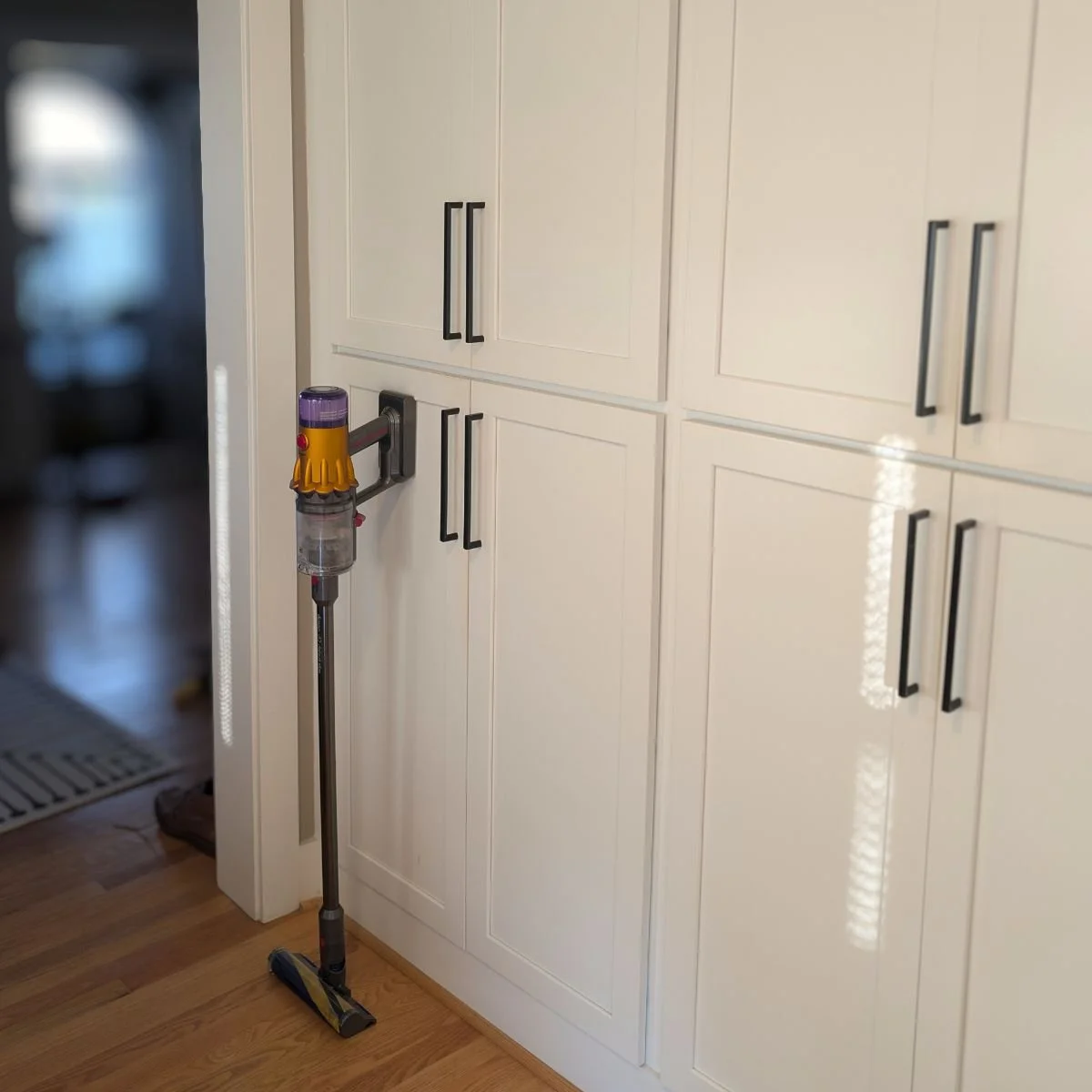Dyson V12 Detect Cordless Vacuum sitting against a wall of white cabinets