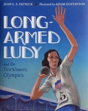 Book cover of "Long-Armed Ludy and the First Women's Olympics" illustrating a woman with long arms holding a shot put, wearing a white shirt with an American flag patch and the number 5, waving with her right hand.